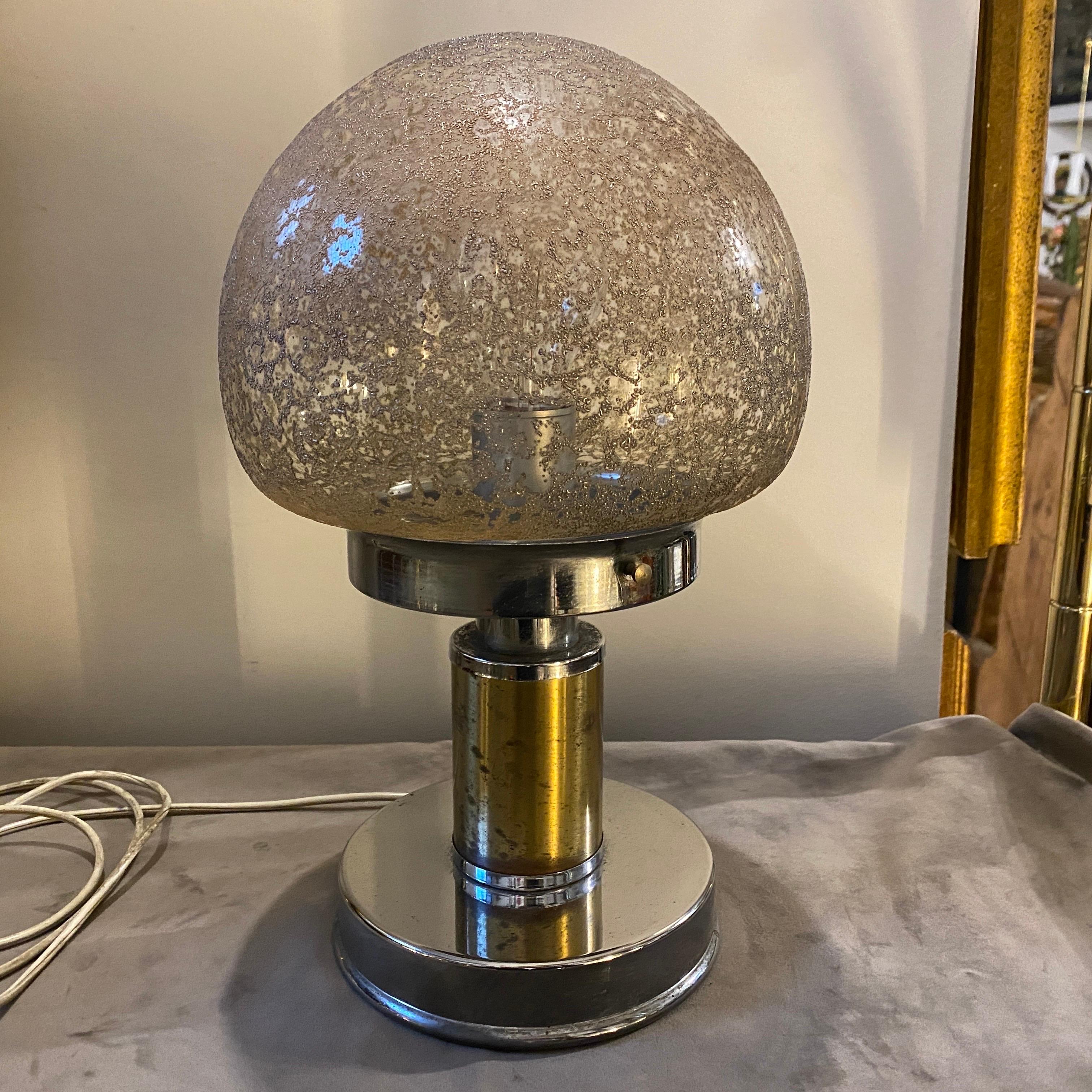 A chromed metal, brass and brown glass table lamp designed and manufactured in Italy in the Space Age era. It's in working order and in lovely conditions, it needs a regular e27 bulb and works both 110-240 volts. The lamp exudes a striking