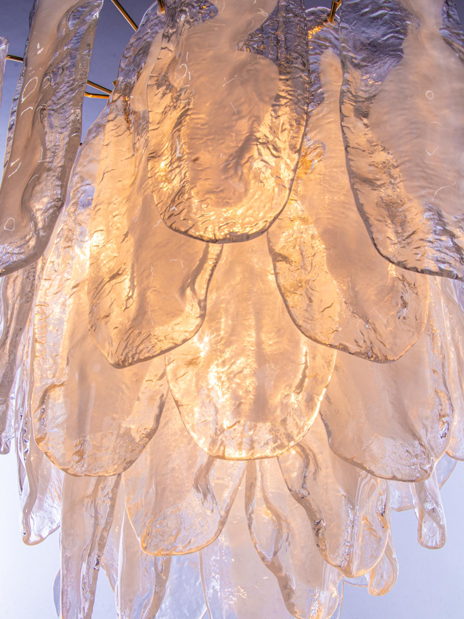 Elegant lustre vintage avec des pétales en verre de Murano soufflé à la main, transparent et teinté en blanc, sur une monture en laiton plaqué or. Fabriqué par Mazzega attr. en Italie dans les années 1970. 

Fabricant : Mazzega attr. 
Dimensions :