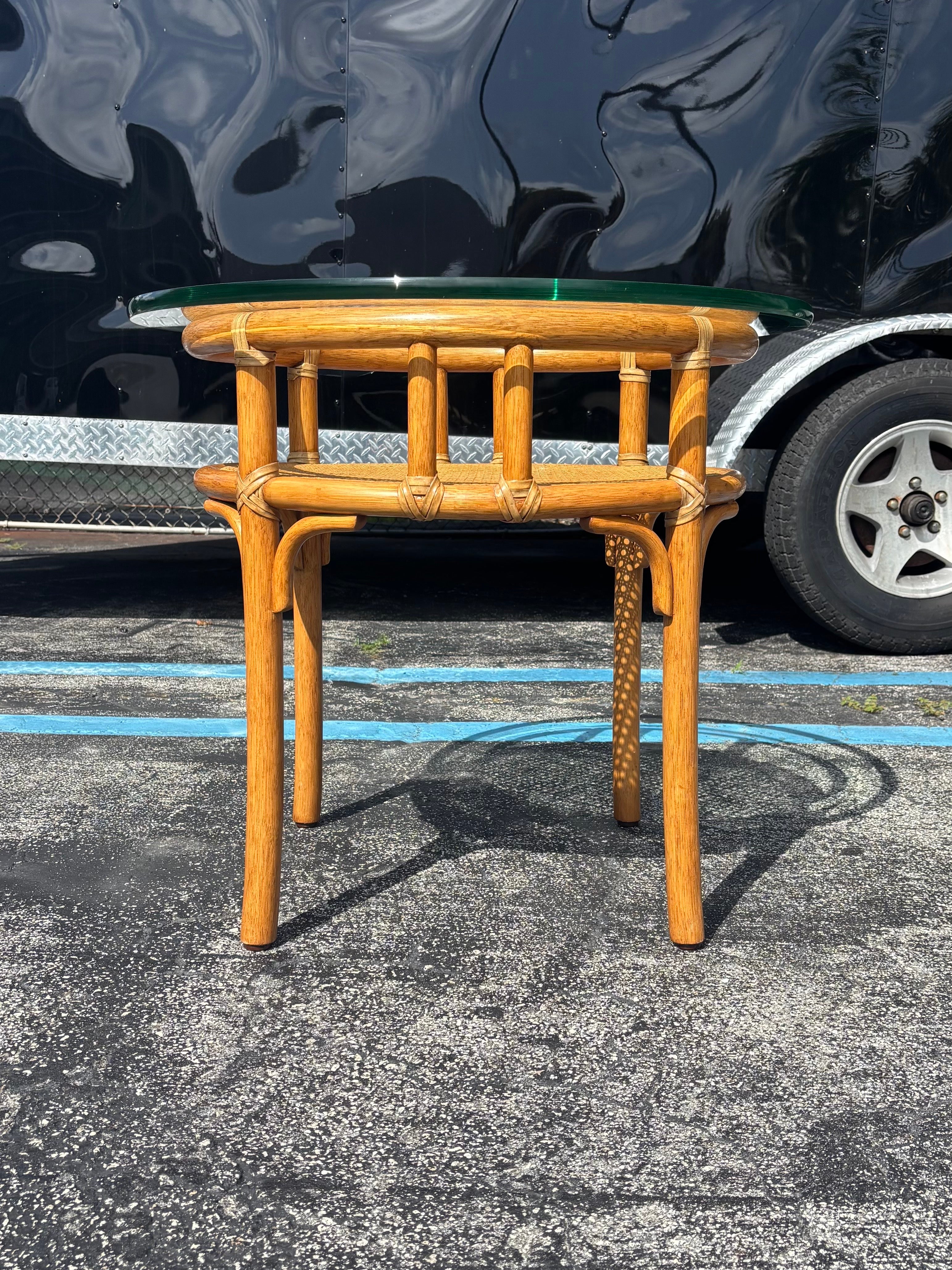 Exceptional two-tier table by McGuire of San Francisco. To be used as a cocktail table, coffee table, or occasional table. 

Featuring a circular rattan frame lashed together with rawhide lacing with a light contrasting cream tone. Bottom shelf is a