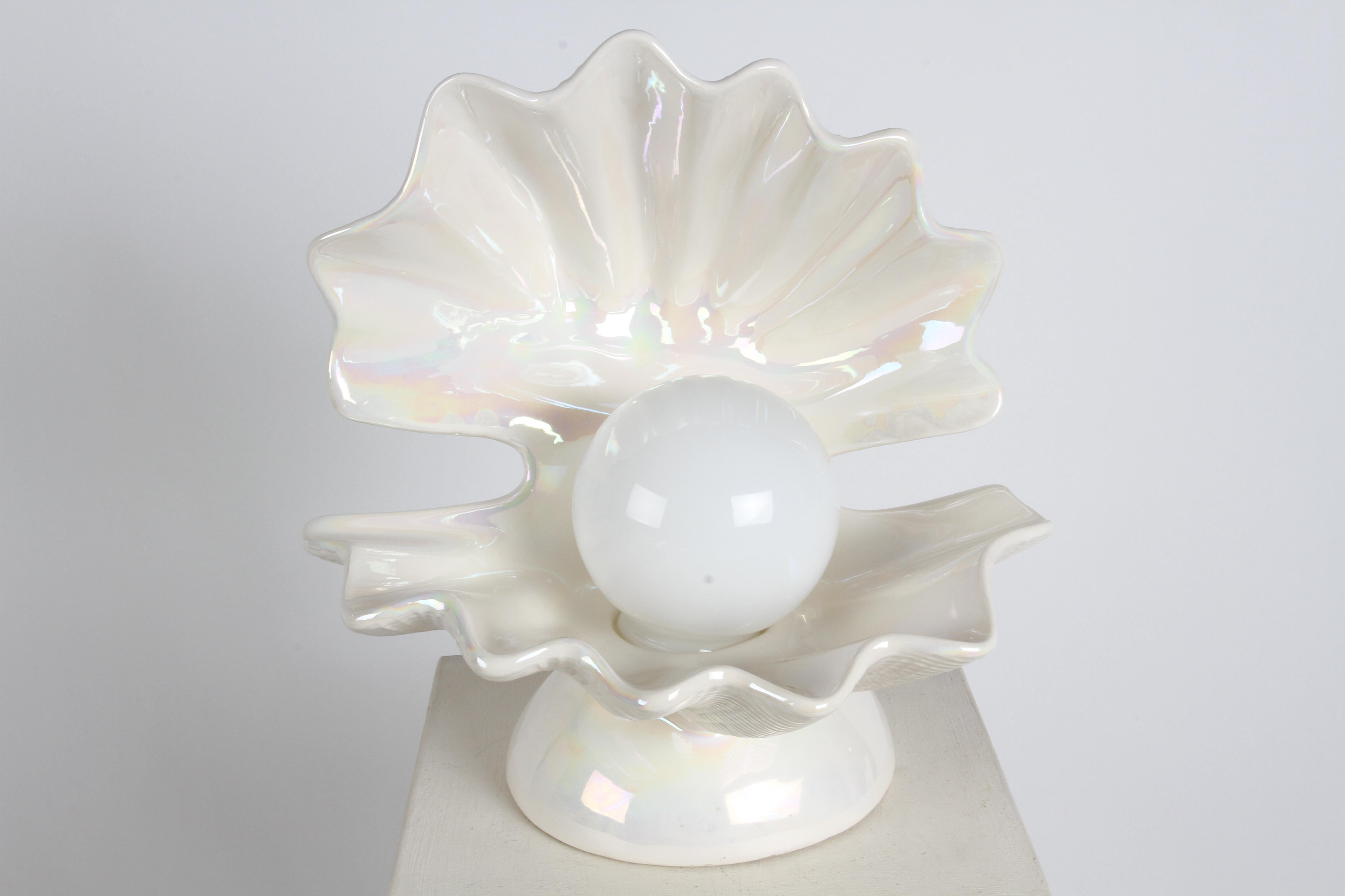  Lampe de table de style Hollywood Regency en céramique de forme ouverte en forme de coquille d'huître sur un piédestal rond surélevé, en émail blanc nacré,  avec un globe blanc en guise de perle. Cette lampe renvoie à la période glamour de l'Art