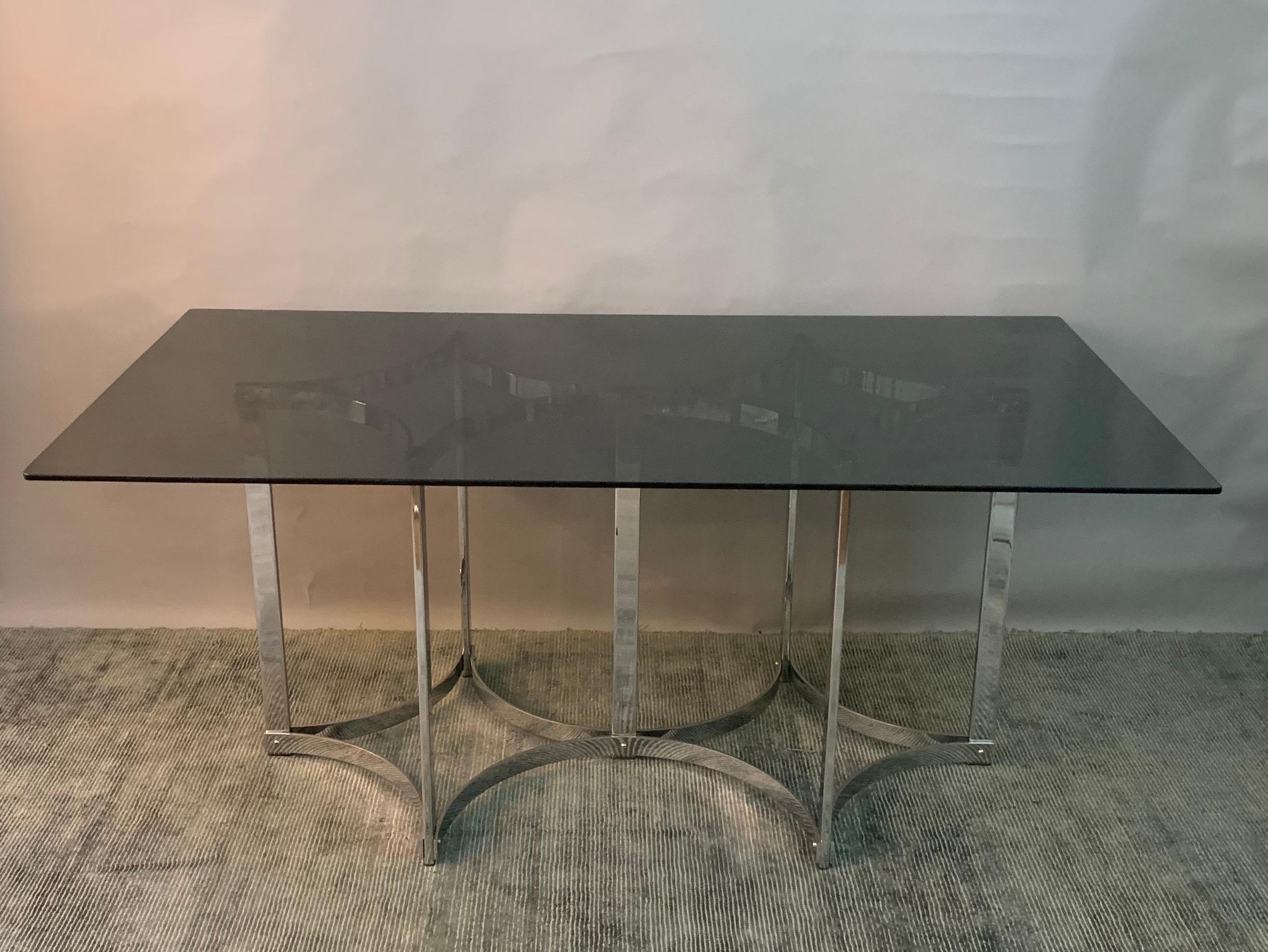 1970s dining table manufactured by upmarket manufacturer Merrow Associates designed by Richard Young. British made. The toughened smoked glass top sits on a double connecting star shaped chrome base. In very good vintage condition with some hardly