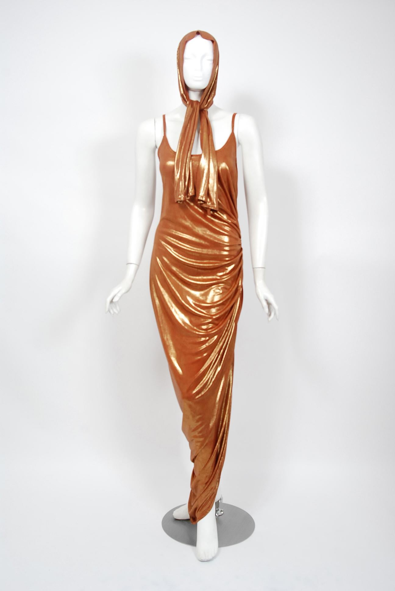 With its vibrant metallic bronze color and flawless styling, this 1970's poly-lurex dress has that disco chicness the 1970's were known for. The low-cut thin strap scoopneck is very flattering and effortless to wear. The one sided ruching is both