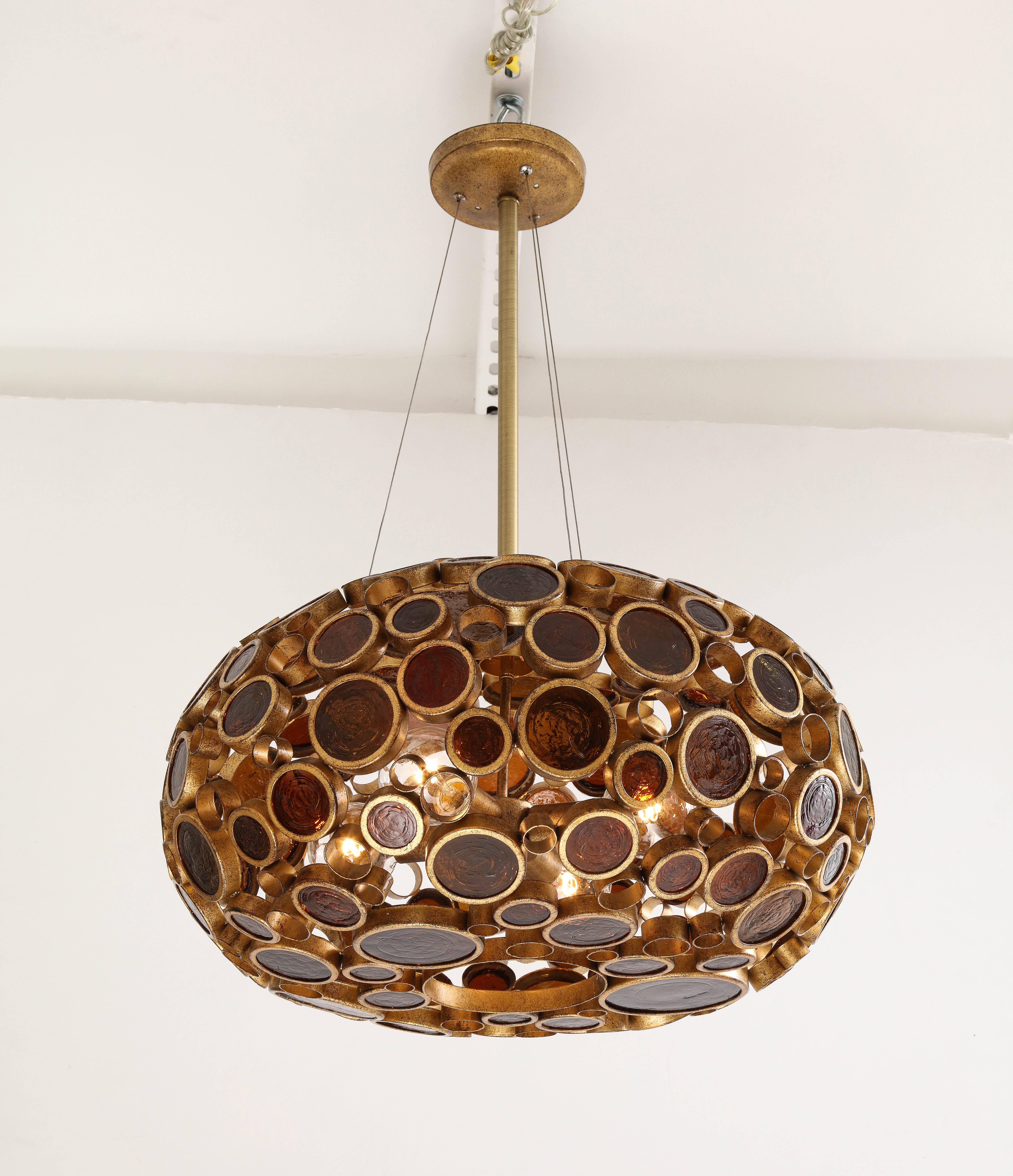 1970s midcentury OP Art glass chandelier.
The Brass fixture has various sized Amber colored glass Rondelays which are illuminated
by four standard light sources.