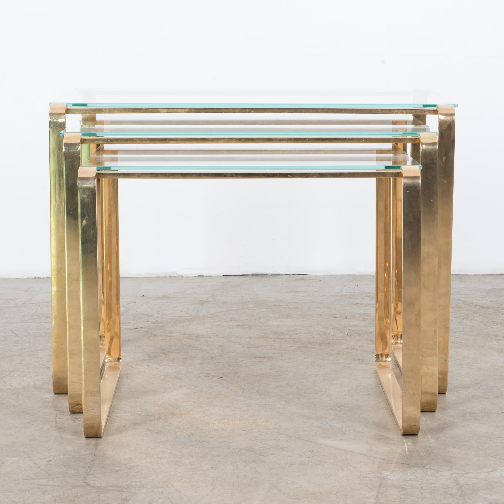 Organic modern metal table legs are brass plated. Convenient nesting configuration allows for free arrangement in the space for variable heights, widths or simply a chic accent. Thick green glass contrasts nicely with the bright and warm brass. This
