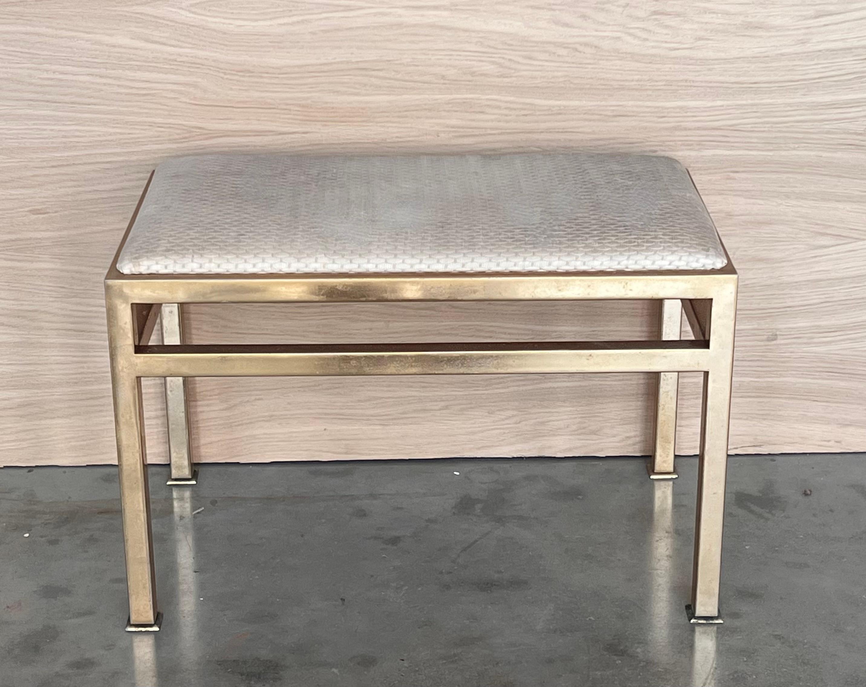 A 1970s modern brass bench or stool with upholstered seat cushion in the style of designer Paul Evans, circa 1970s.