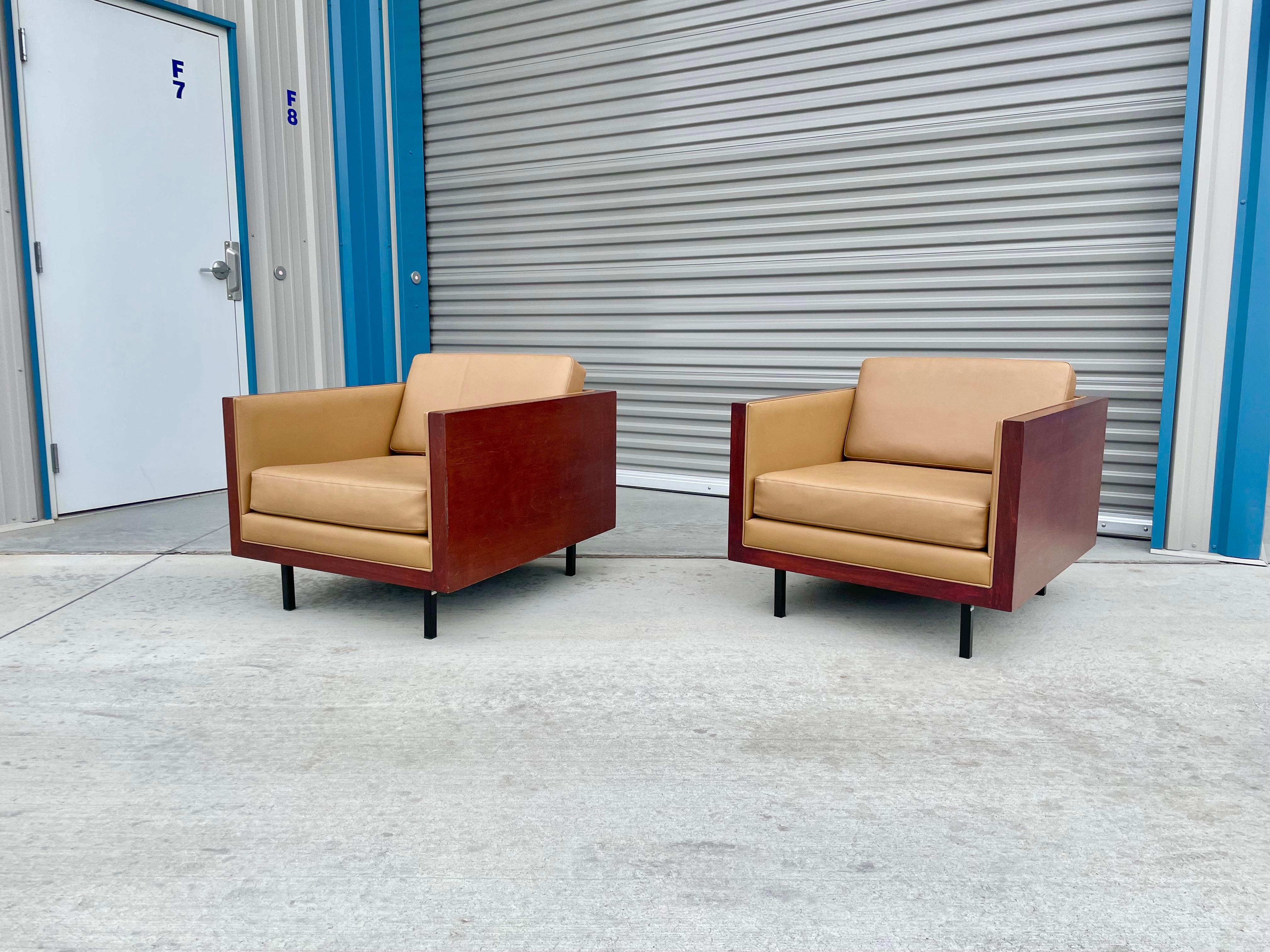 Mid-century cube lounge chairs were designed and manufactured in the United States circa 1970s. These beautiful lounge chairs feature a wooden cube shape design. The chairs are also covered in a brown vinyl upholstery fabric that is in good shape