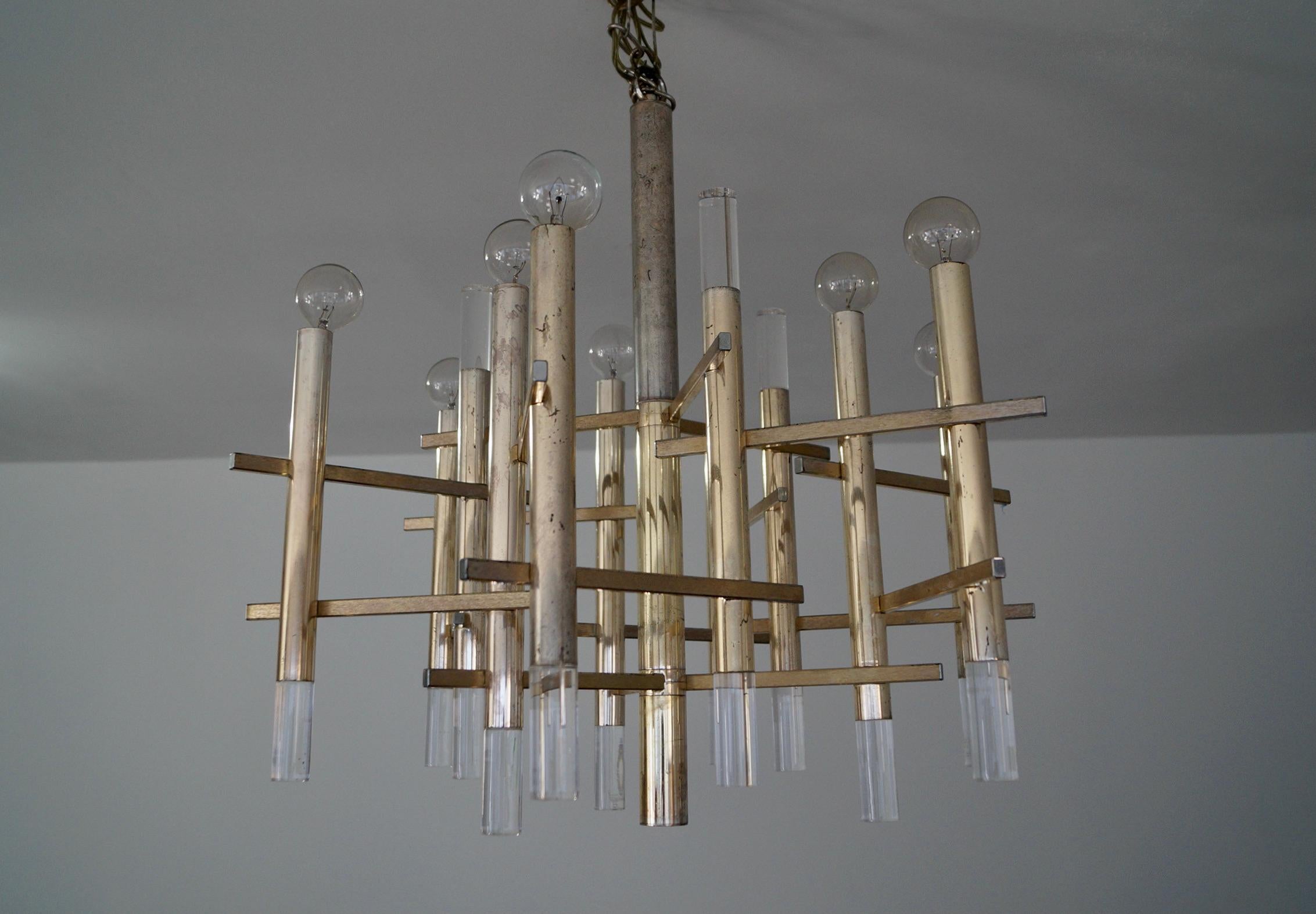 Vintage Mid century Modern chandelier for sale. Designed by Gaetano Sciolari in 1970, and has been professionally re-wired. It’s made of aluminum in a brass finish with lucite cylinders. It’s in good vintage condition with some vintage patina. It