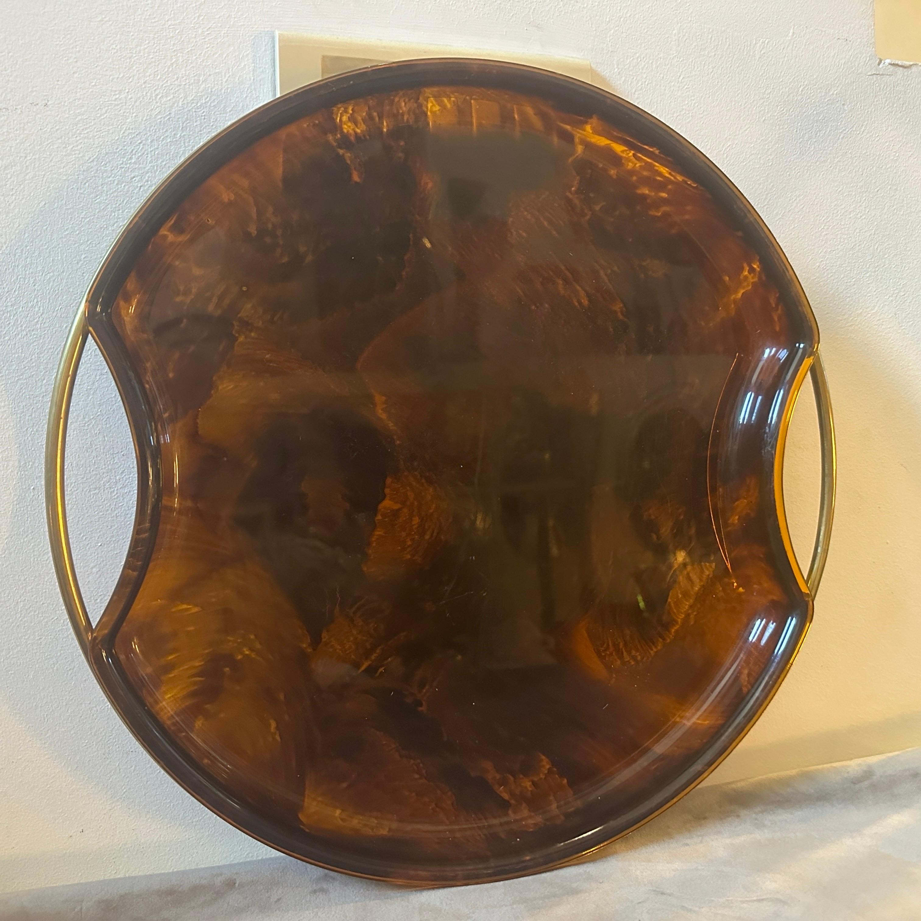A Modernist Fake Tortoise Lucite and Brass round tray designed and manufactured by the Italian design company Guzzini during the 1970s in lovely conditions. The Guzzini company is a well-known Italian brand that specializes in the production of