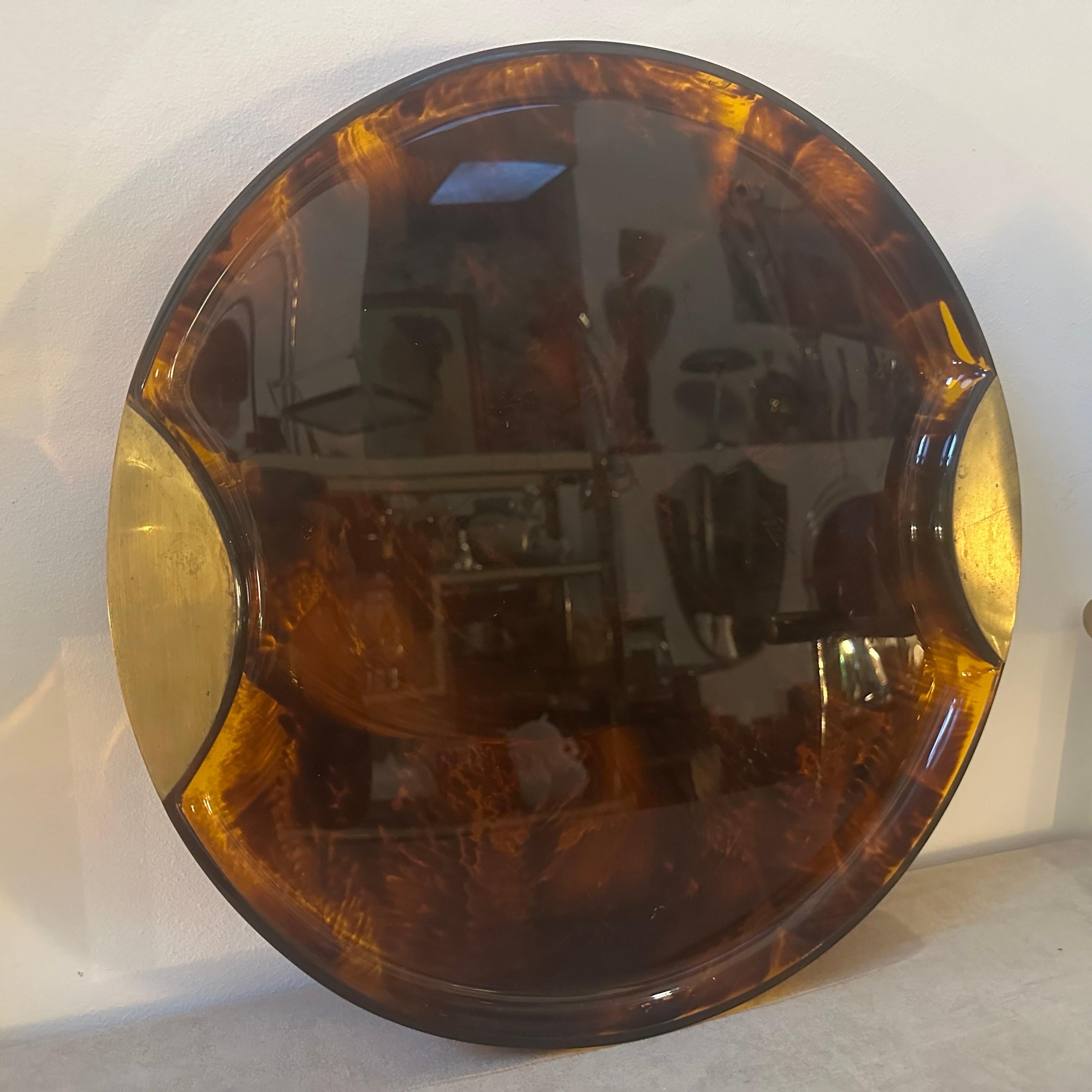 A Modernist Fake Tortoise Lucite and Brass round tray designed and manufactured by the Italian design company Guzzini during the 1970s in lovely conditions. The Guzzini company is a well-known Italian brand that specializes in the production of
