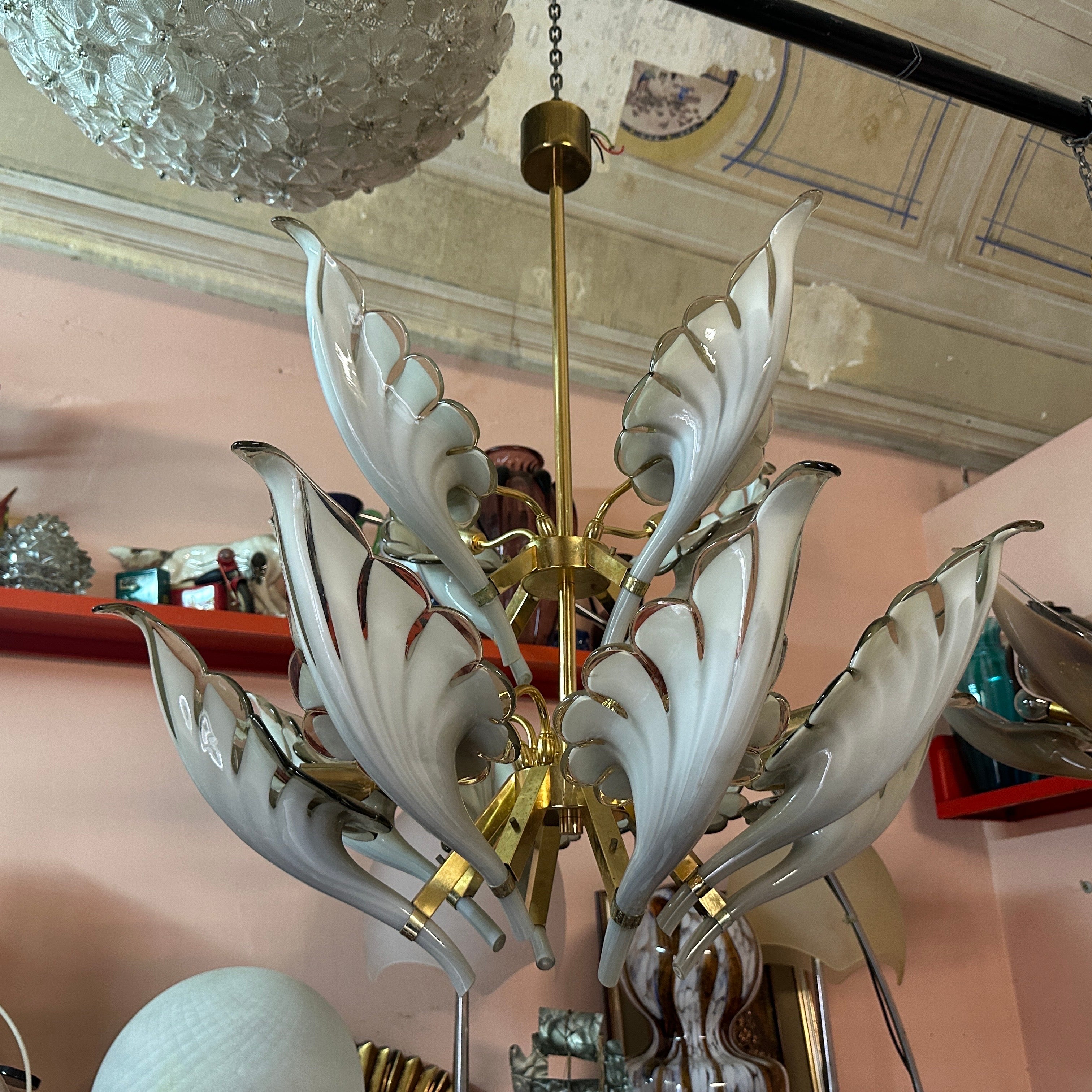 This chandelier is a striking example of Mid-Century Modern design with a touch of Hollywood Regency flair. It's glamorous yet restrained, featuring a harmonious blend of warm brass tones and delicate gray Murano glass. The design is both organic