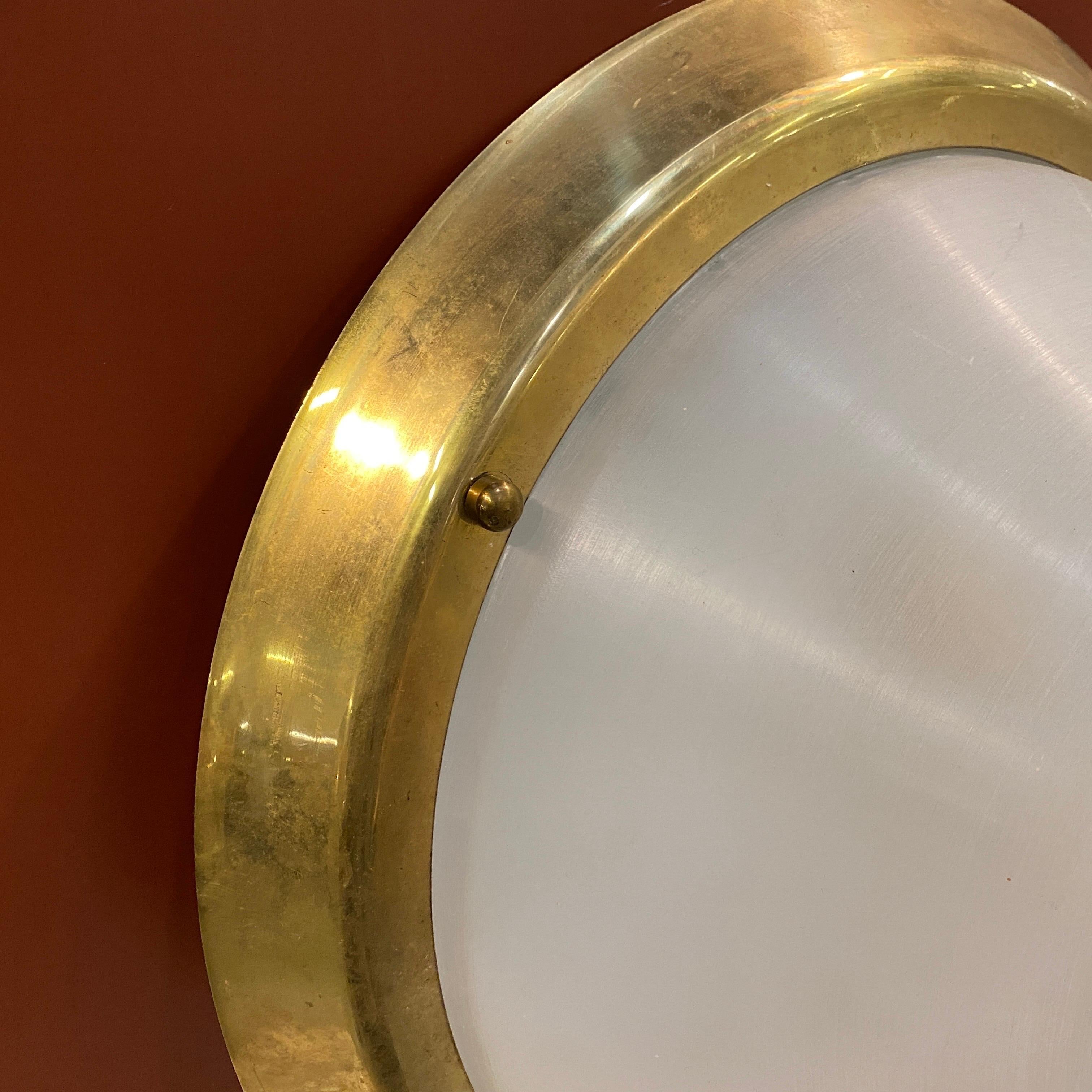 A round brass and plexiglass ceiling light designed and manufactured in Italy in the Seventies in the style of Stilux. It works both 110-240 volts and needs regular e27 bulbs. it's in working order and in lovely conditions. Brass in original patina