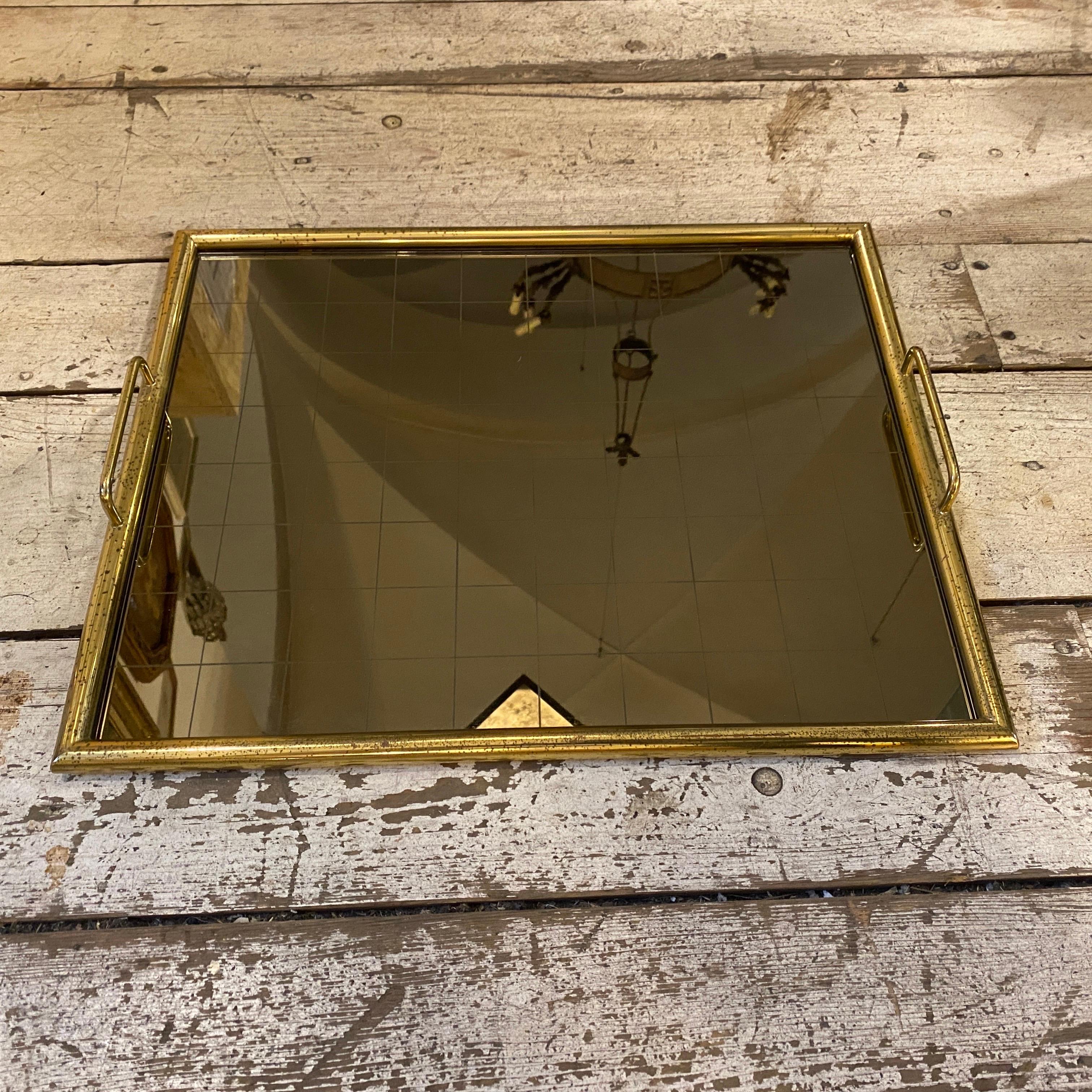A brass and smoked glass rectangular tray designed and manufactured in the Seventies in the style of Tommaso Barbi, it's in good conditions overall with normal signs of use and age. Its structure crafted from high-quality brass, showcasing a