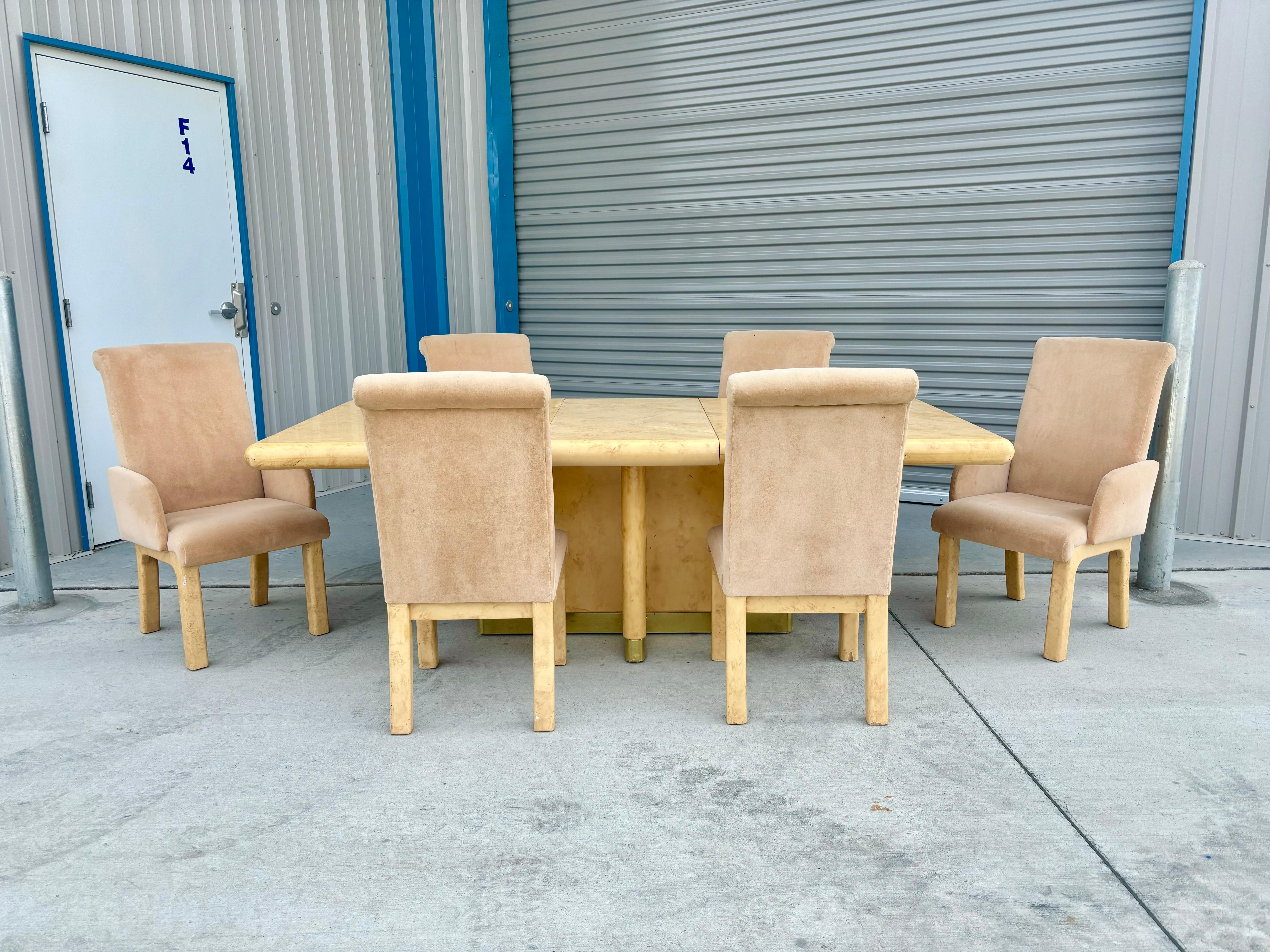 Cet ensemble de salle à manger en loupe moderne du milieu du siècle a été conçu et fabriqué aux États-Unis dans les années 1970. Cette saisissante table de salle à manger rectangulaire est soutenue par un magnifique piètement en ronce et laiton, qui