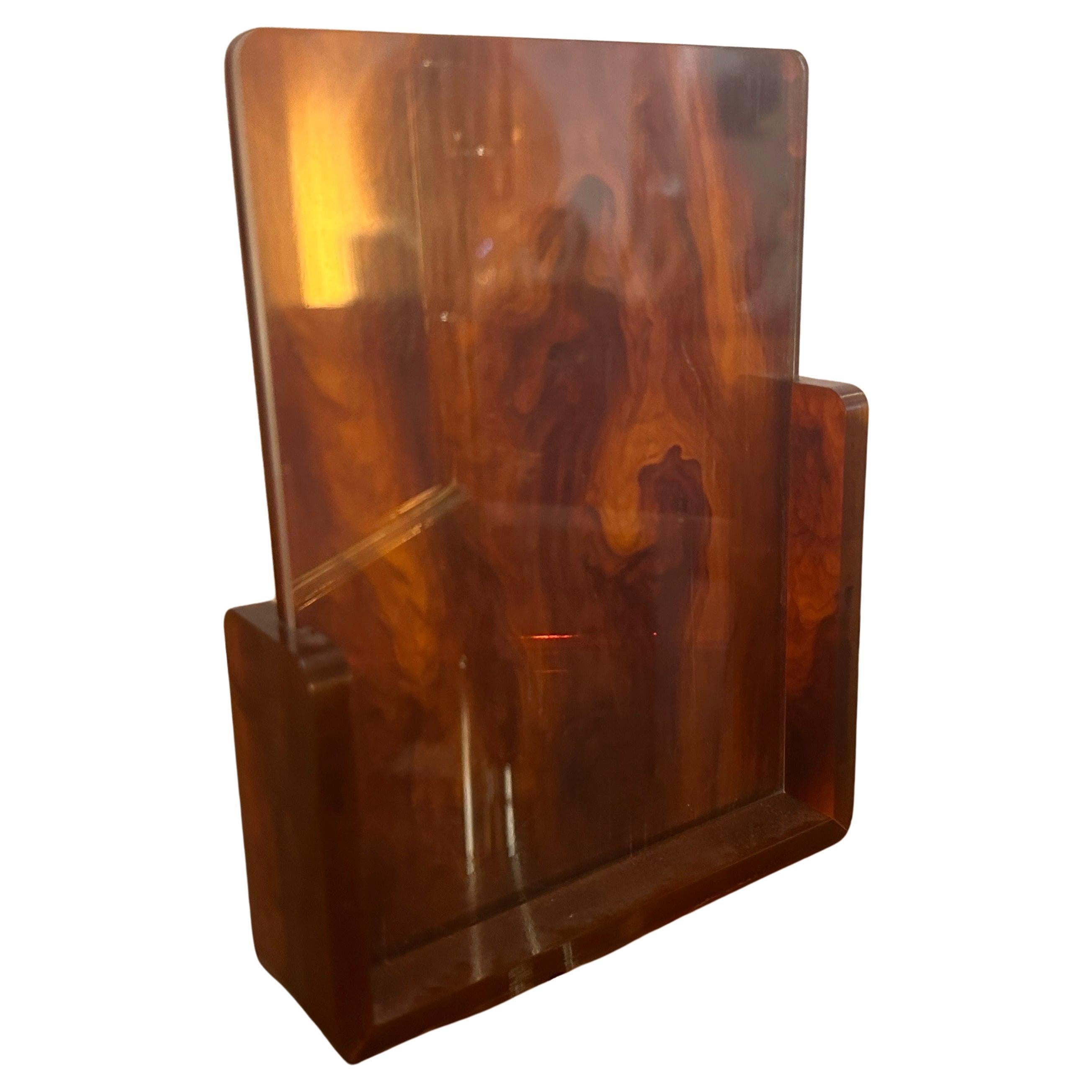 This 1970s Picture Frame is a stylish and distinctive piece of decor that reflects the design trends of its era. The frame is crafted from Lucite, a type of acrylic glass known for its transparency, durability, and lightweight properties. It