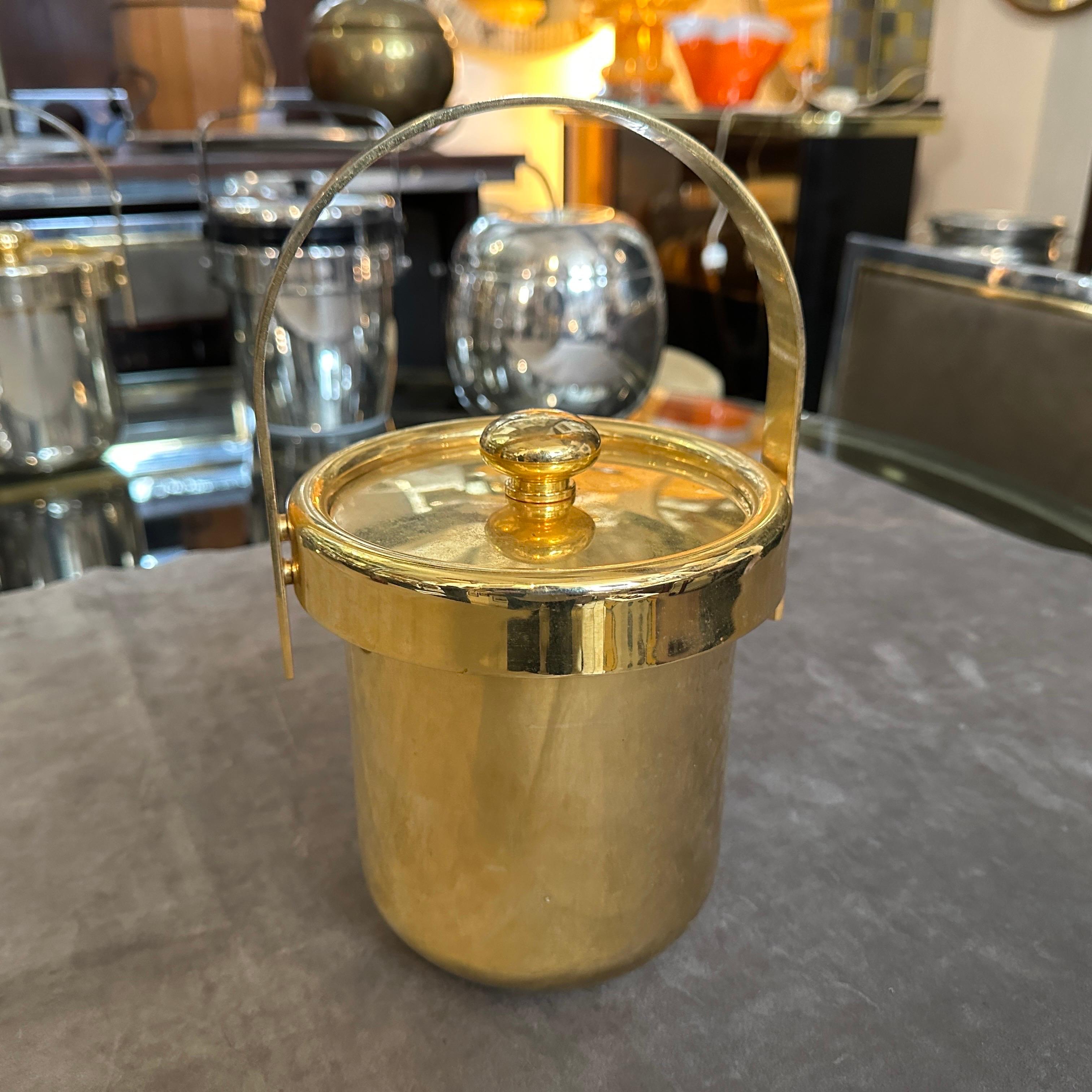 This is a 1970s Mid-Century Modern Italian ice bucket crafted from gilded metal. The bucket features a sleek cylindrical form with a polished gold-tone finish, reflecting the era's love for luxurious yet minimalist design.
The removable lid is