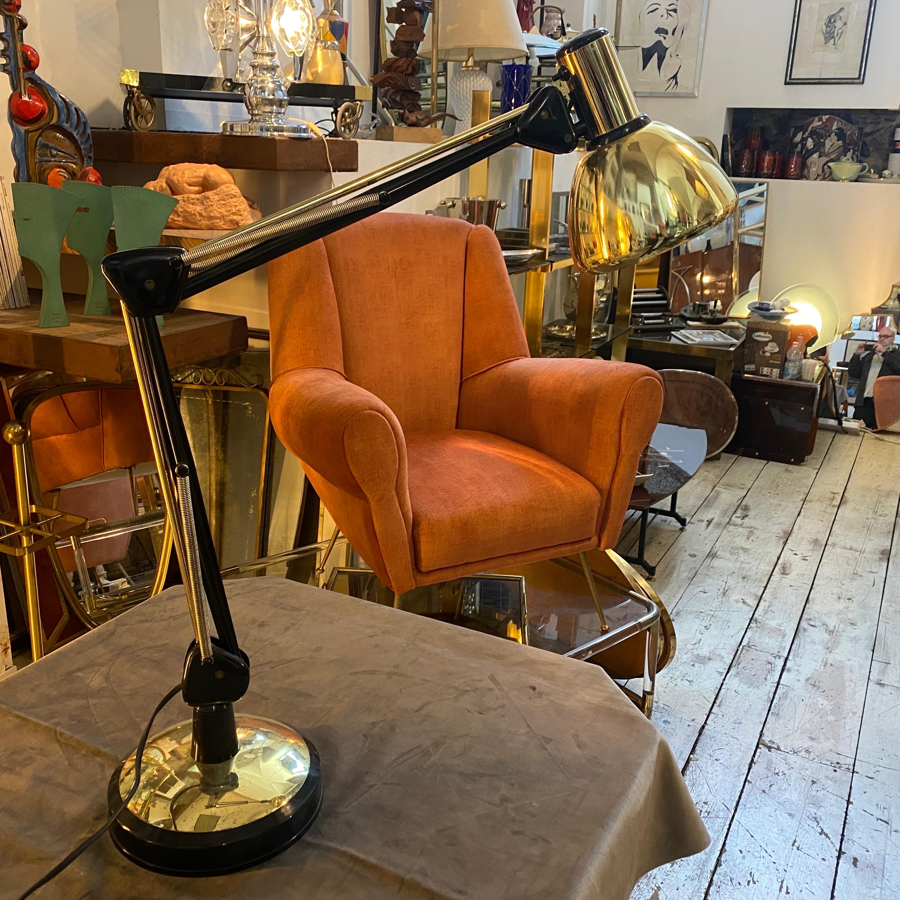 A gilt metal and plastic desk lamp designed and manufactured in Italy in the seventies in very good conditions overall. It's in working order. The desk lamp is a sleek and functional lighting fixture that embodies the design principles of the era.