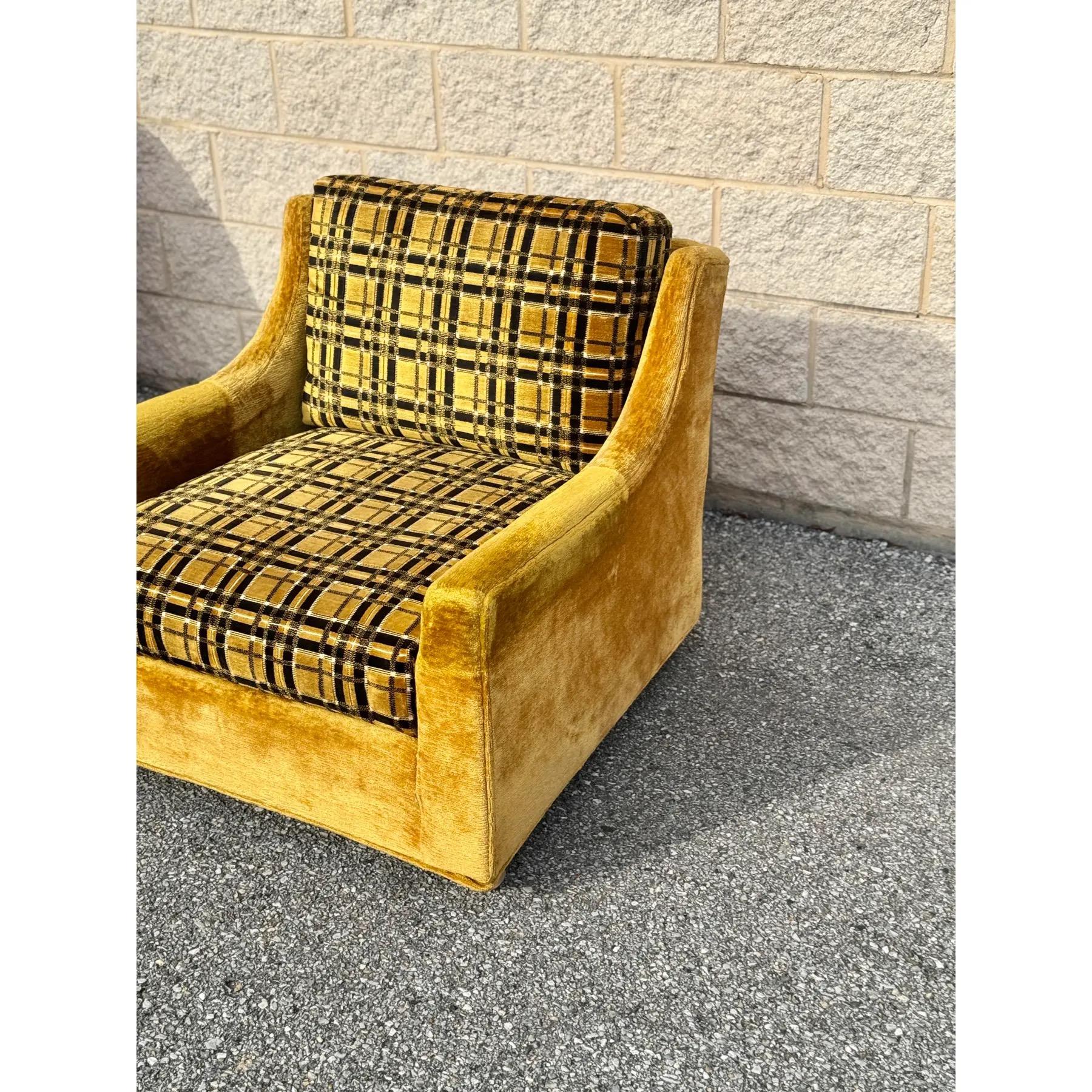 A mid-century modern lounge chair from the 1970s, featuring gold velvet upholstery complemented by a plaid fabric seat and back cushion. 

