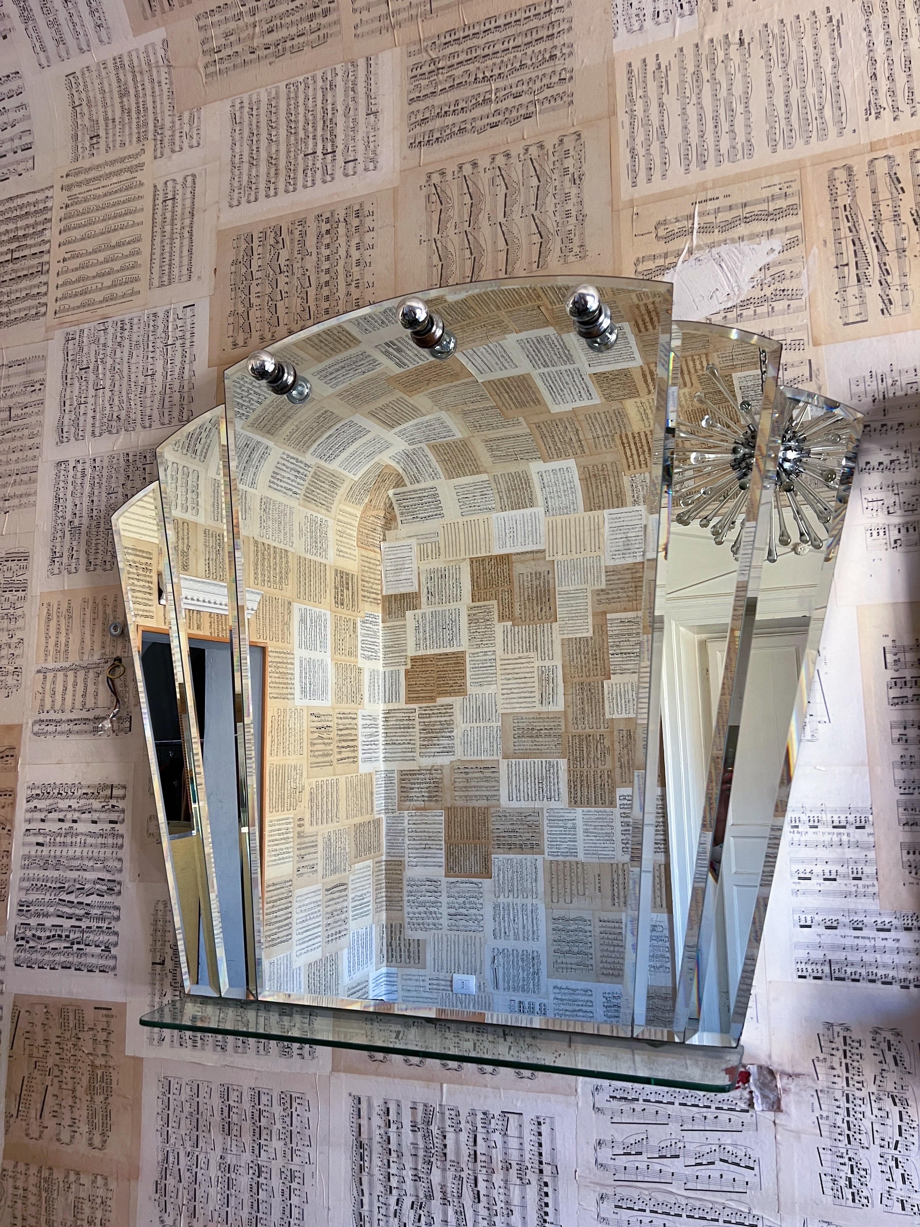 Dieser exquisite italienische Wandspiegel aus den 1970er Jahren ist ein außergewöhnliches Stück. Er ist mit hochwertigem Spiegelglas ausgestattet, das schön reflektiert. Der Spiegel ist mit drei E14-Fassungen für die Beleuchtung ausgestattet und