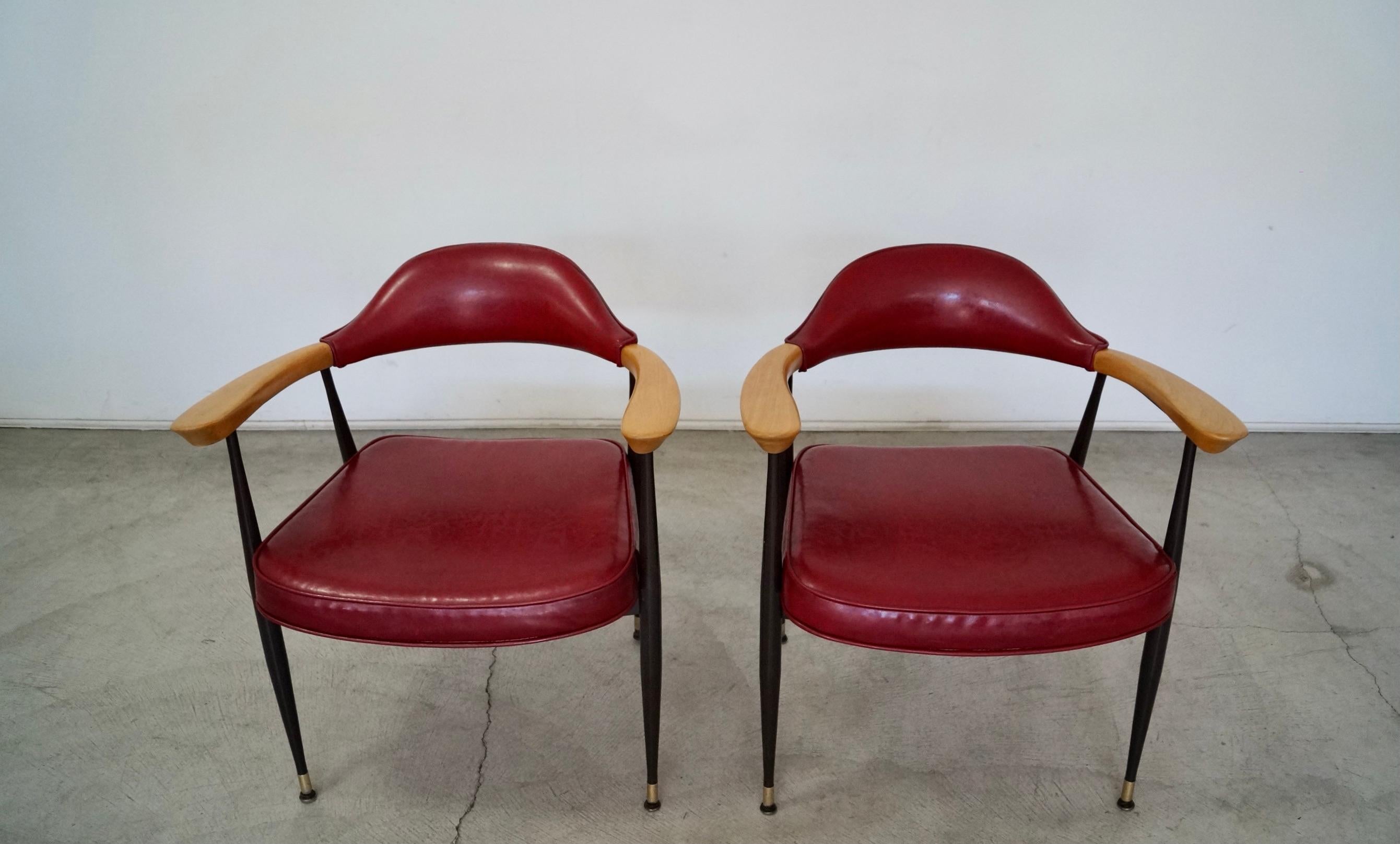 Vintage Mid-century Modern armchairs for sale. Manufactured in 1977 by Lion Brand, and still have the original maker's mark underneath. They have the original red vinyl in excellent vintage condition. The solid oak arms have been refinished in