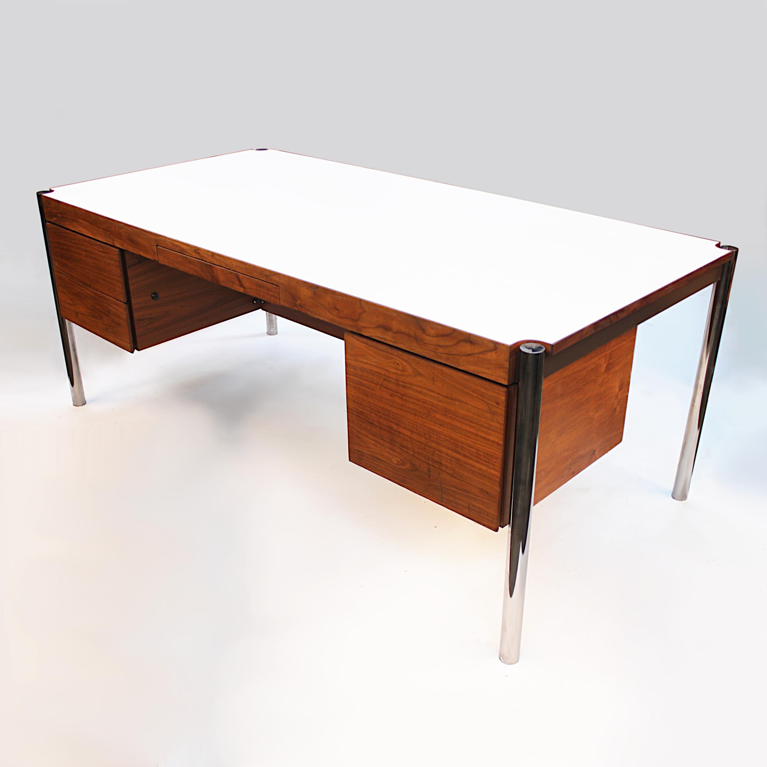 This unique executive desk was designed by Jens Risom and produced by Howe Furniture in the mid-late 1970s. The desk features Minimalist lines accented by 'floating' chrome legs, oiled-walnut cabinets and white Formica top! With its beautifully
