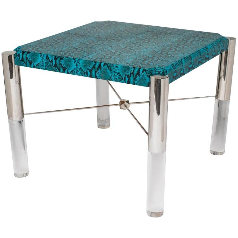 Stunning Mid-Century Modern game table features a genuine leather top in vibrant turquoise with embossed python pattern. Square table with shield top design. Solid lucite cylinder legs with chromed tops.  Fitted with X-crossbars held by a geometric