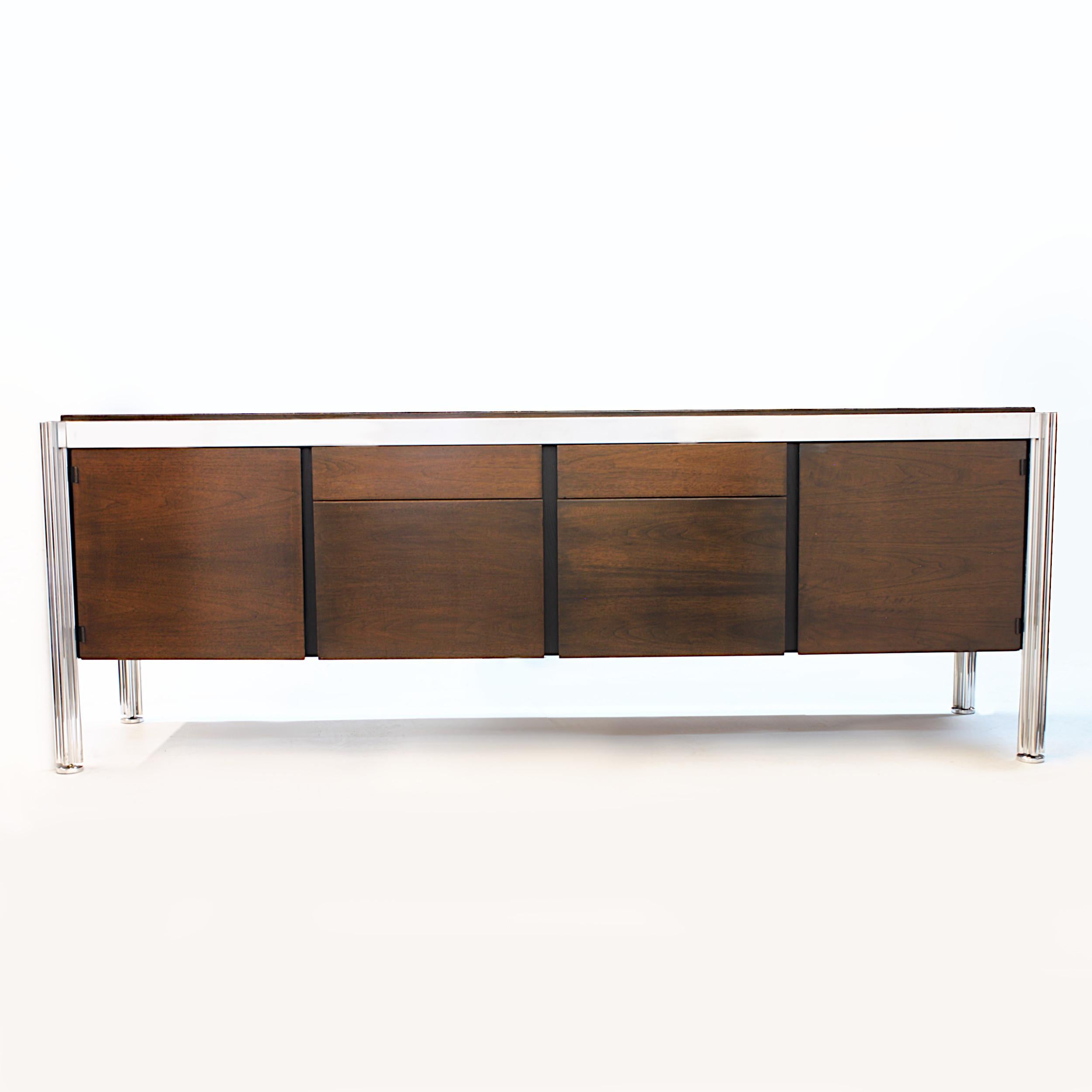 Amazing 1970s walnut and aluminum credenza designed by George Ciancimino for Jens Risom Furniture. Credenza features a sleek, Minimalist design, four center drawers, flanked by two single-door cabinets and unique puzzle-shaped aluminum legs. Would