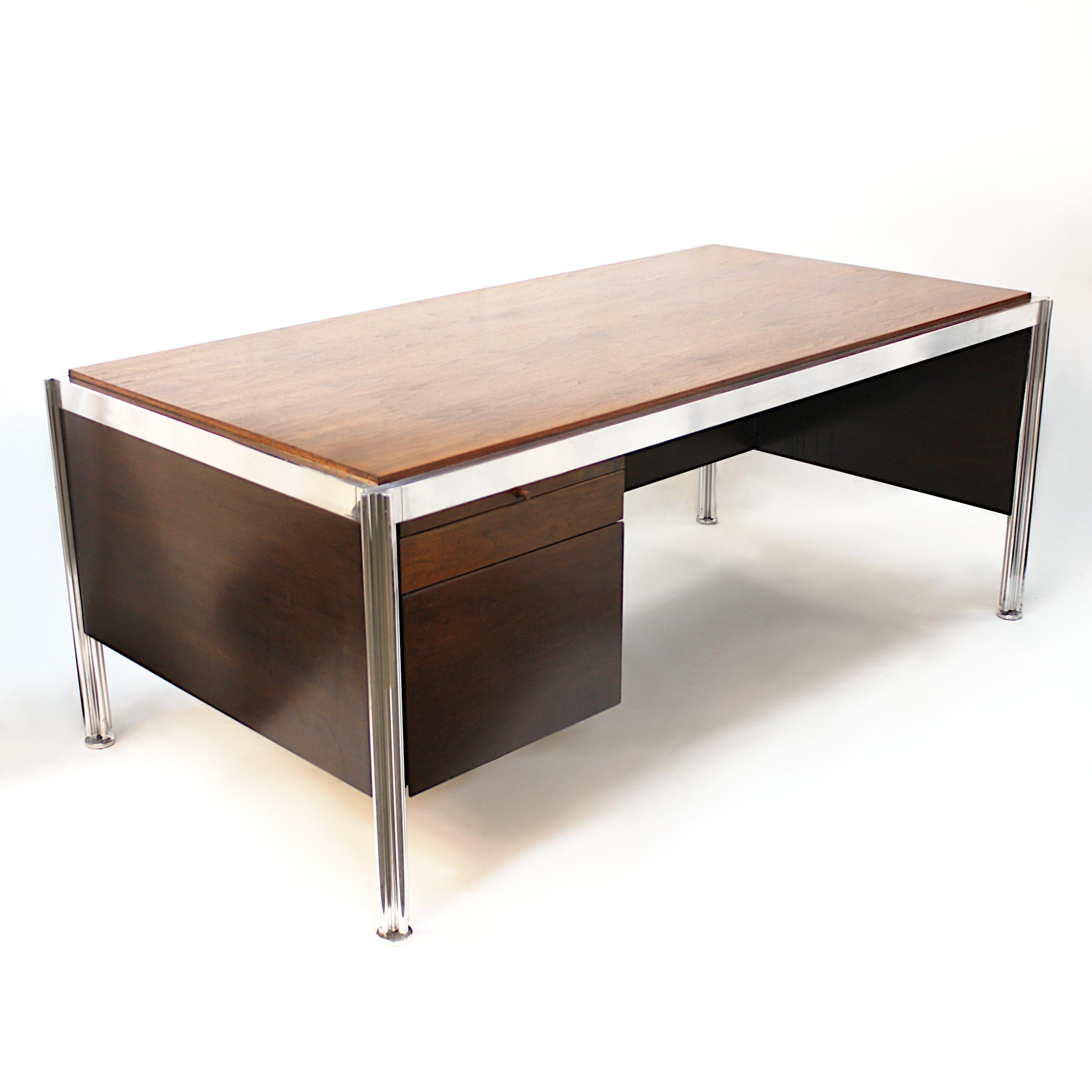Amazing 1970s walnut and aluminum executive desk designed by George Ciancimino for Jens Risom Furniture. Desk features a sleek, Minimalist design, two drawers, two slide-out tablets, and unique, puzzle-shaped aluminum legs. Would make an impressive