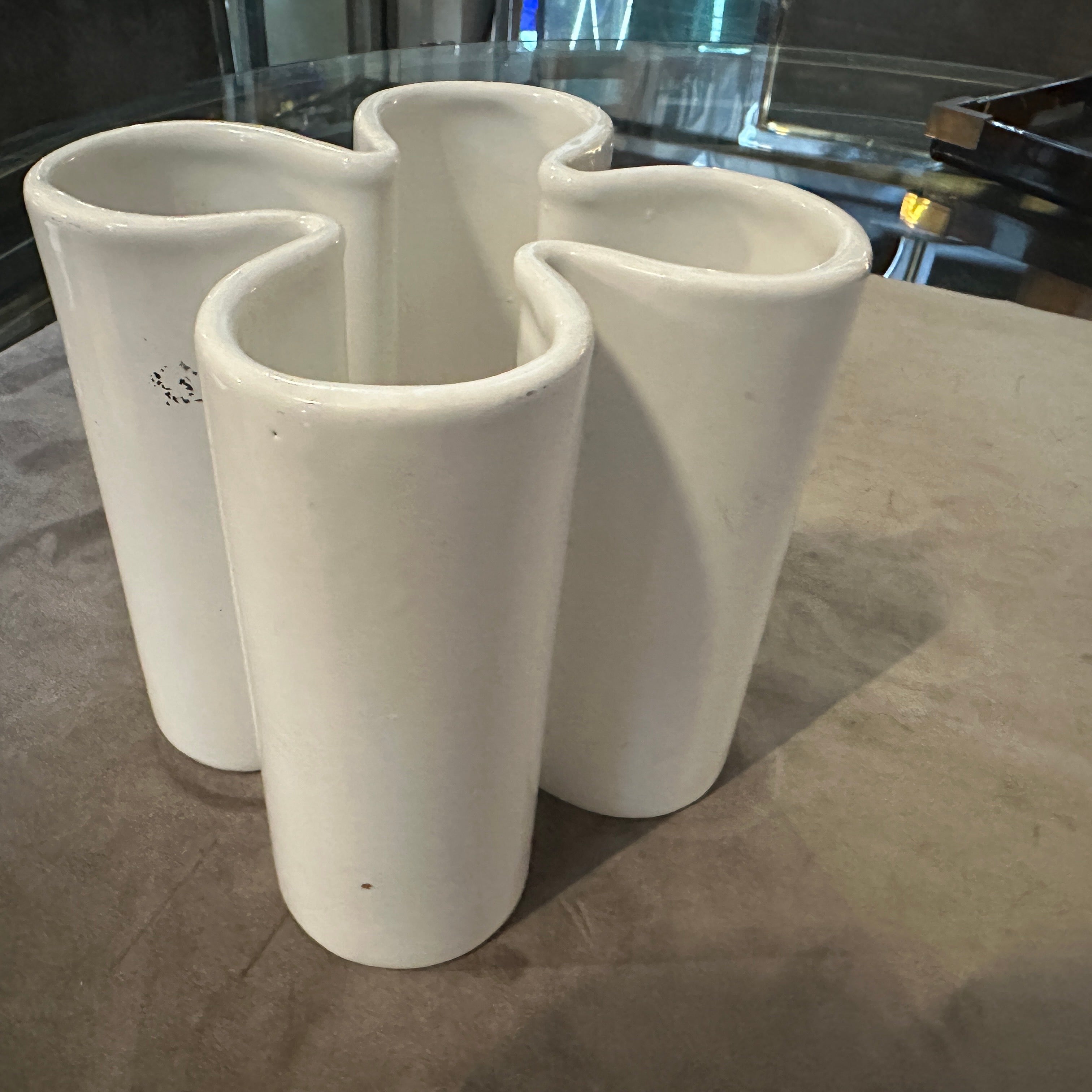 This unique and stylish ceramic vase, designed by the iconic Pierre Cardin, is a perfect representation of 1970s mid-century modern design. The piece features an abstract, sculptural form resembling a four-leaf clover, with four distinct cylindrical