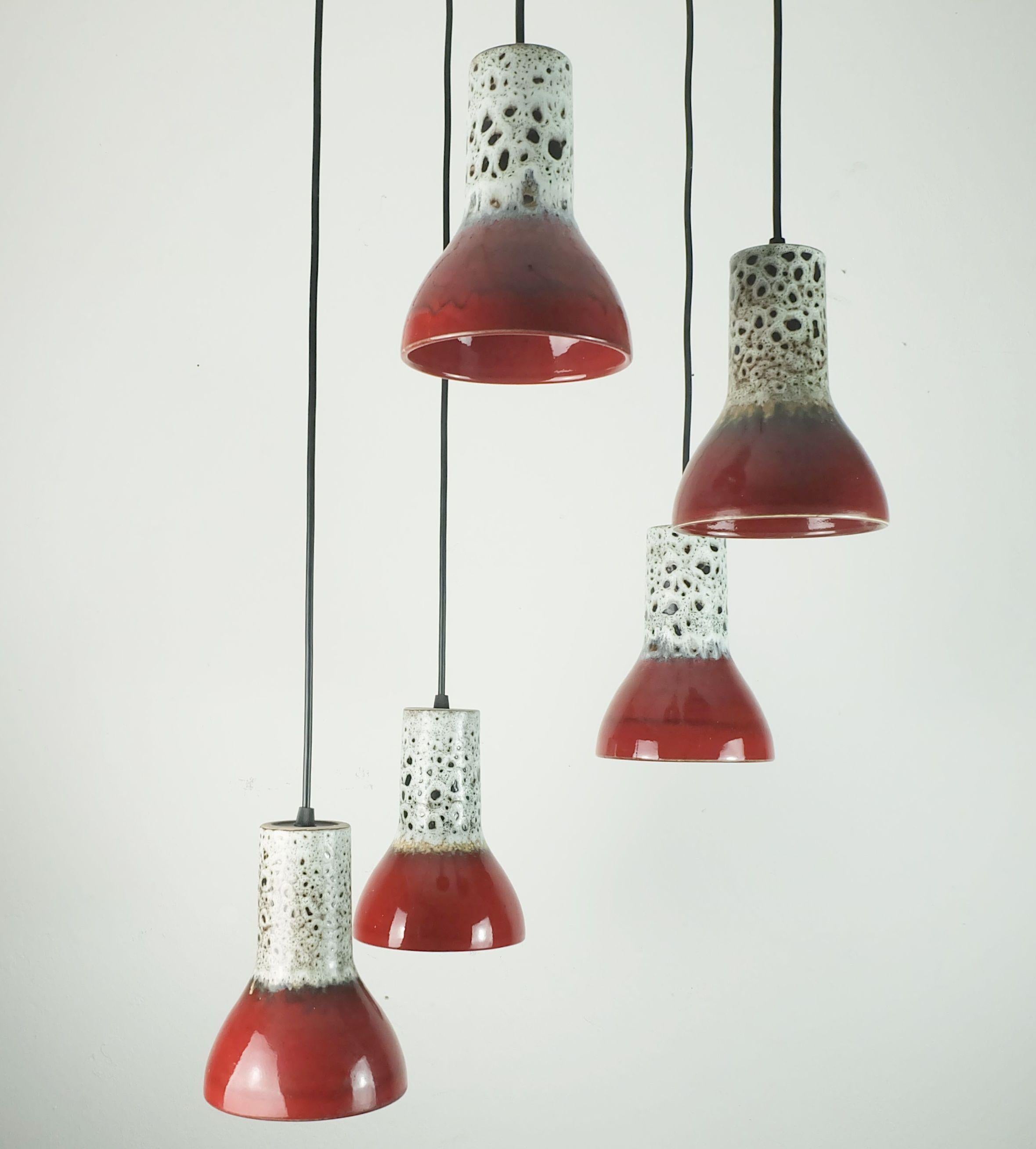 Preciosa lámpara colgante de 5 luces de mediados de siglo XX. Son de cerámica con esmalte de lava grasa en blanco y tonos beige y marrón combinados con esmalte rojo oscuro. Cables eléctricos negros. La parte superior es de plástico de color negro y
