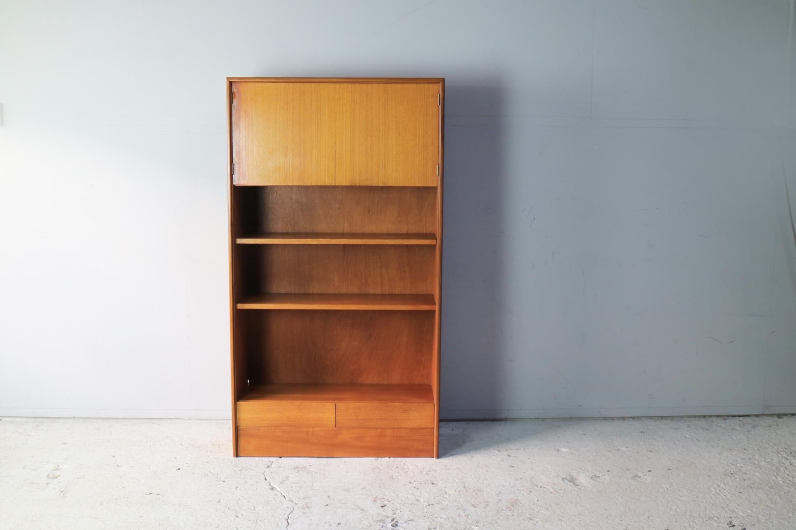 Rare book shelf or storage unit by G Plan. Minimally designed with a Danish sensibility. Two cupboards at the top and 2 drawers at the bottom. Open book shelving in between. G Plan label on inside of cupboard door.
 