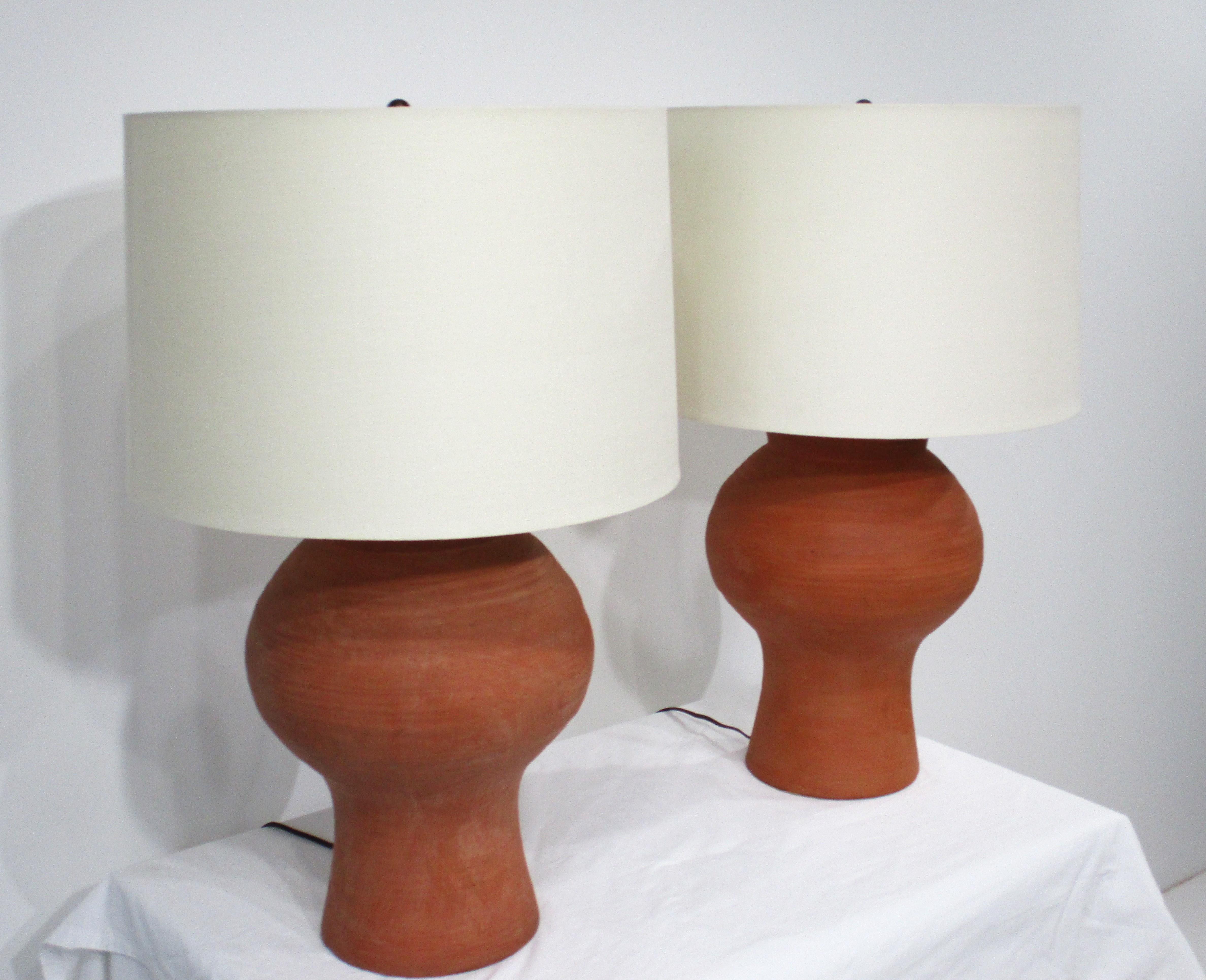 Ein Paar skulpturale, wohlgeformte Terrakotta-Tischlampen mit cremefarbenen Leinen-Tonnenschirmen. Die in den 1970er Jahren entworfenen Lampen passen zu jeder Einrichtung, jedem Stil und jedem Raum und haben eine einfache, saubere und warme
