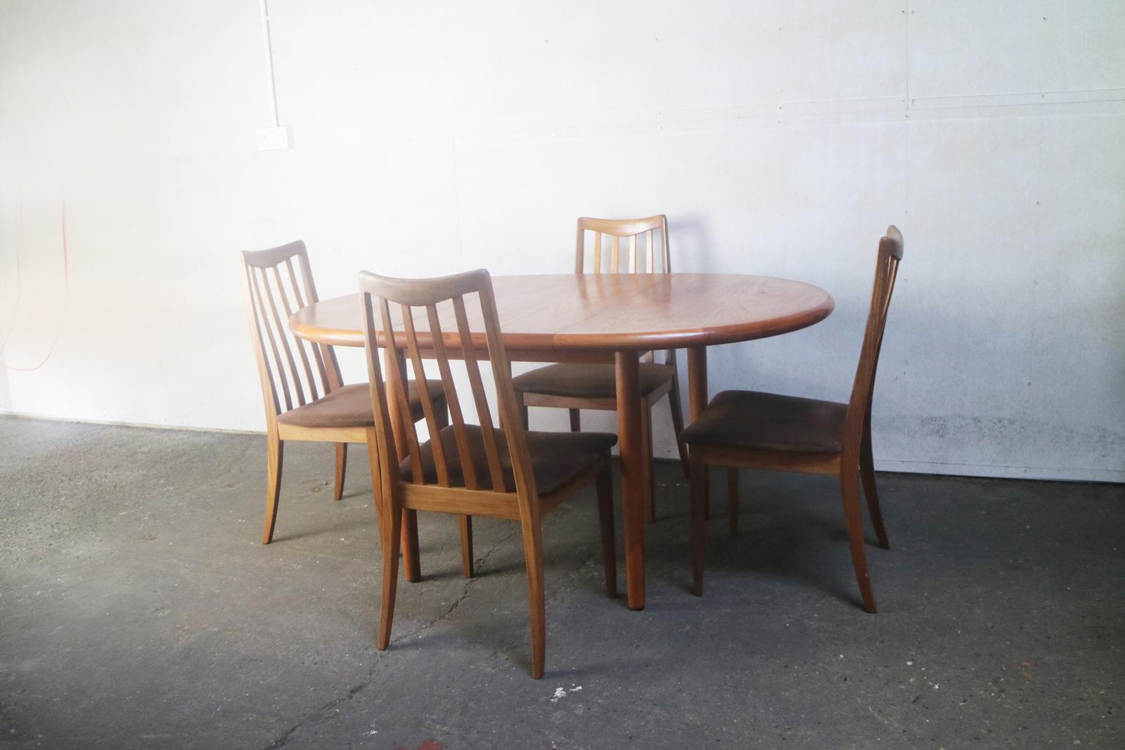 A very fine, relatively small extending Danish dining table with lovely wood grain, thick rounded edges and decorative inlaid edging. The six G Plan chairs are elegantly shaped, with brown velour seating and distinctive back rests.

Table is
