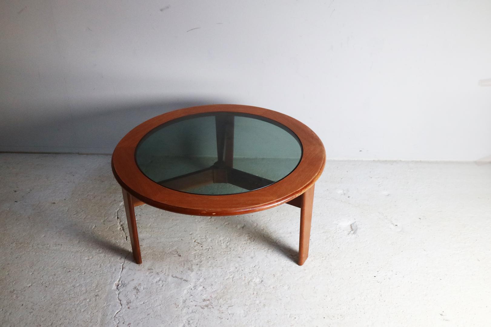 A round coffee table with solid teak frame and smoked glass inset. By G plan and in fine condition.