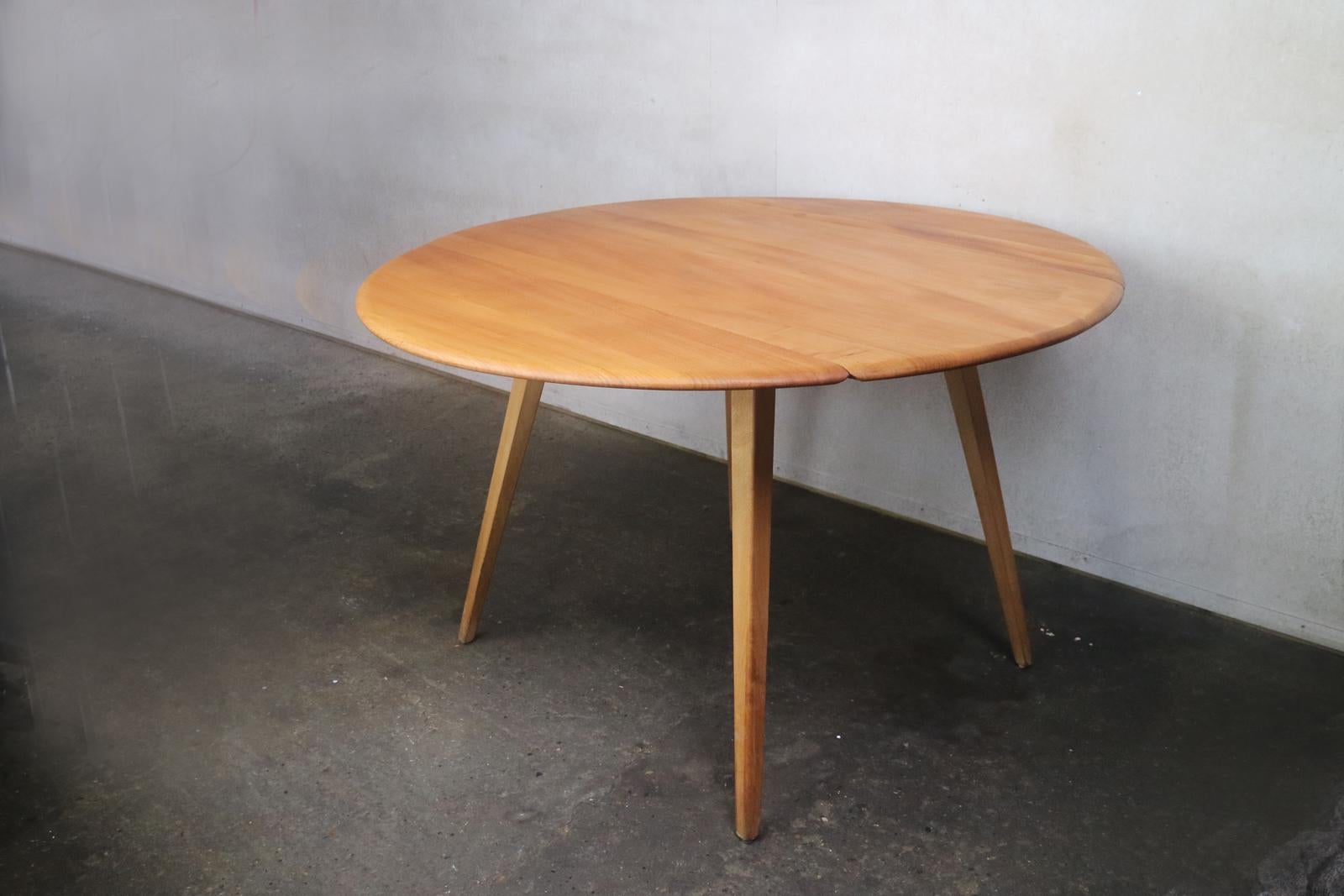 This light colored drop-leaf table has proven to be a popular and Classic Ercol design since the mid-1950s. Raised on splayed tapering solid beech legs, the solid elm tabletop converts from an oblong to the circular shape.