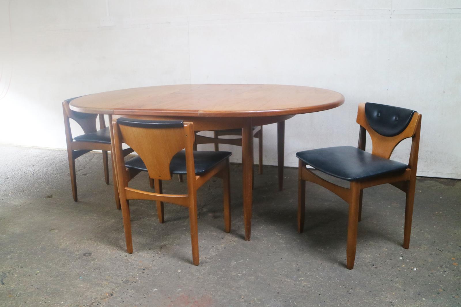 The low backs of these dining chairs create a stylish look for this Mid-Century Modern dining set. The table is by G plan and extends by means of a central flap.

The chairs are upholstered in the original black vinyl with button detail on the