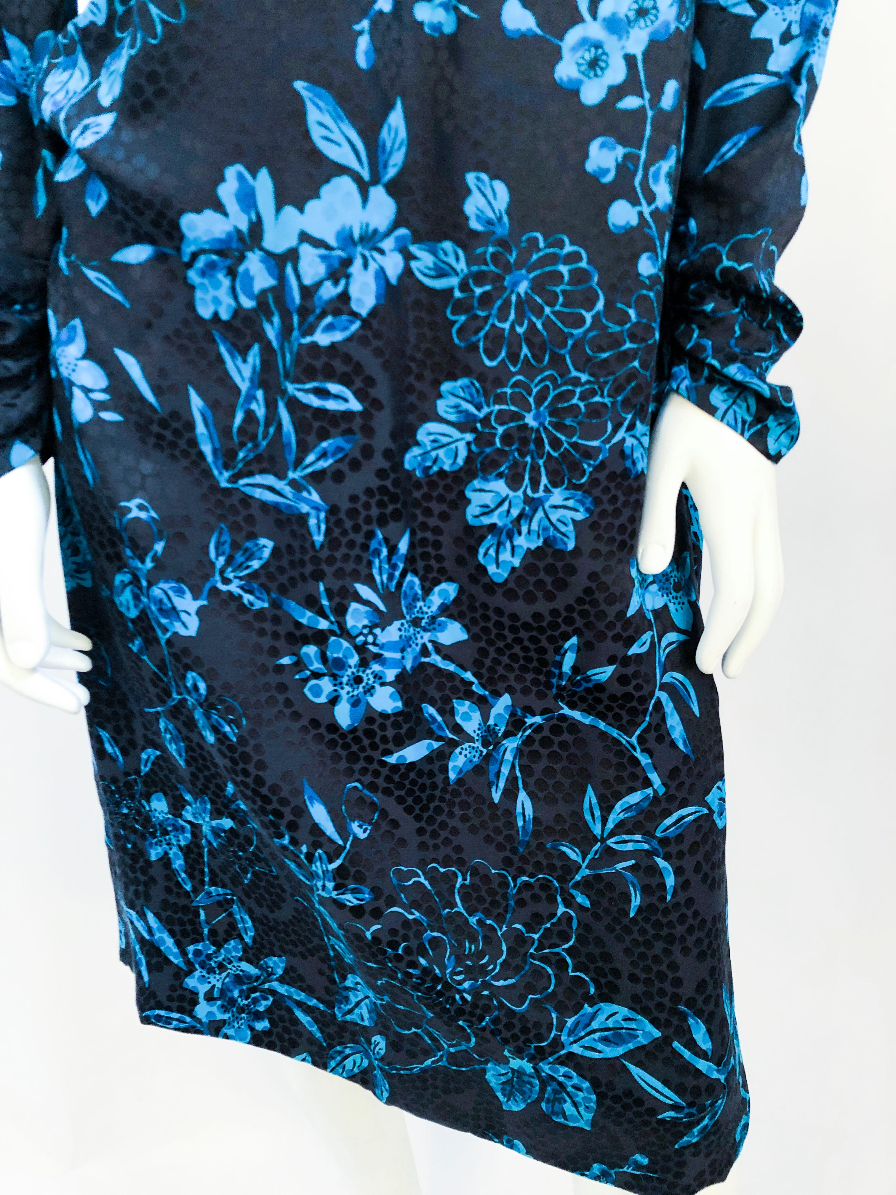 !970's silk floral printed dress with blue-toned flowers and a black fore-color that makes the ornate pattern on the jacquard. The dress also has a high collar that is roused on the face that crates a gathered effect on the entire dress. The long