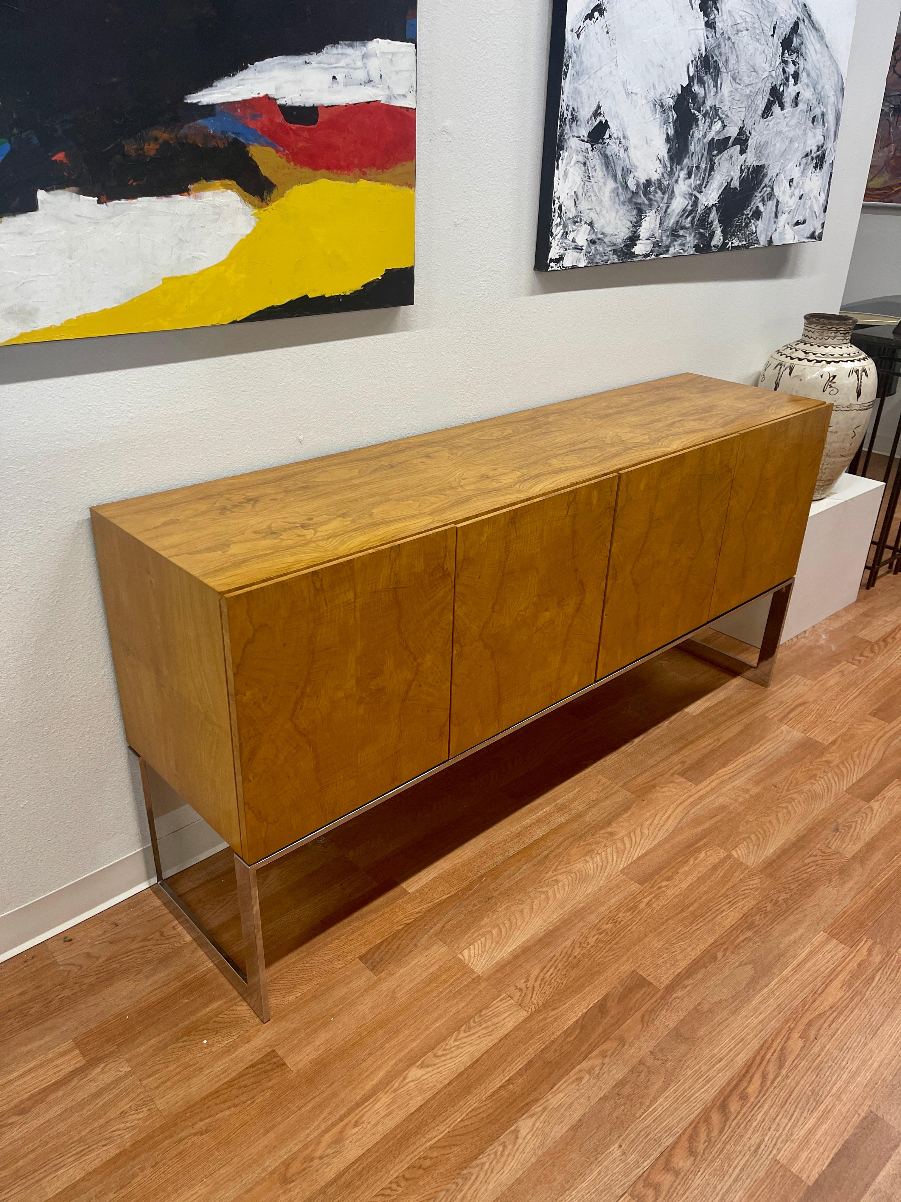 Richly grained burl wood veneered credenza by Milo Baughman for Thayer Coggin. Circa 1970’s. White painted interior. On chromed steel base. The exterior is in good condition, with minor marks. The interior has some spots of missing paint and rough