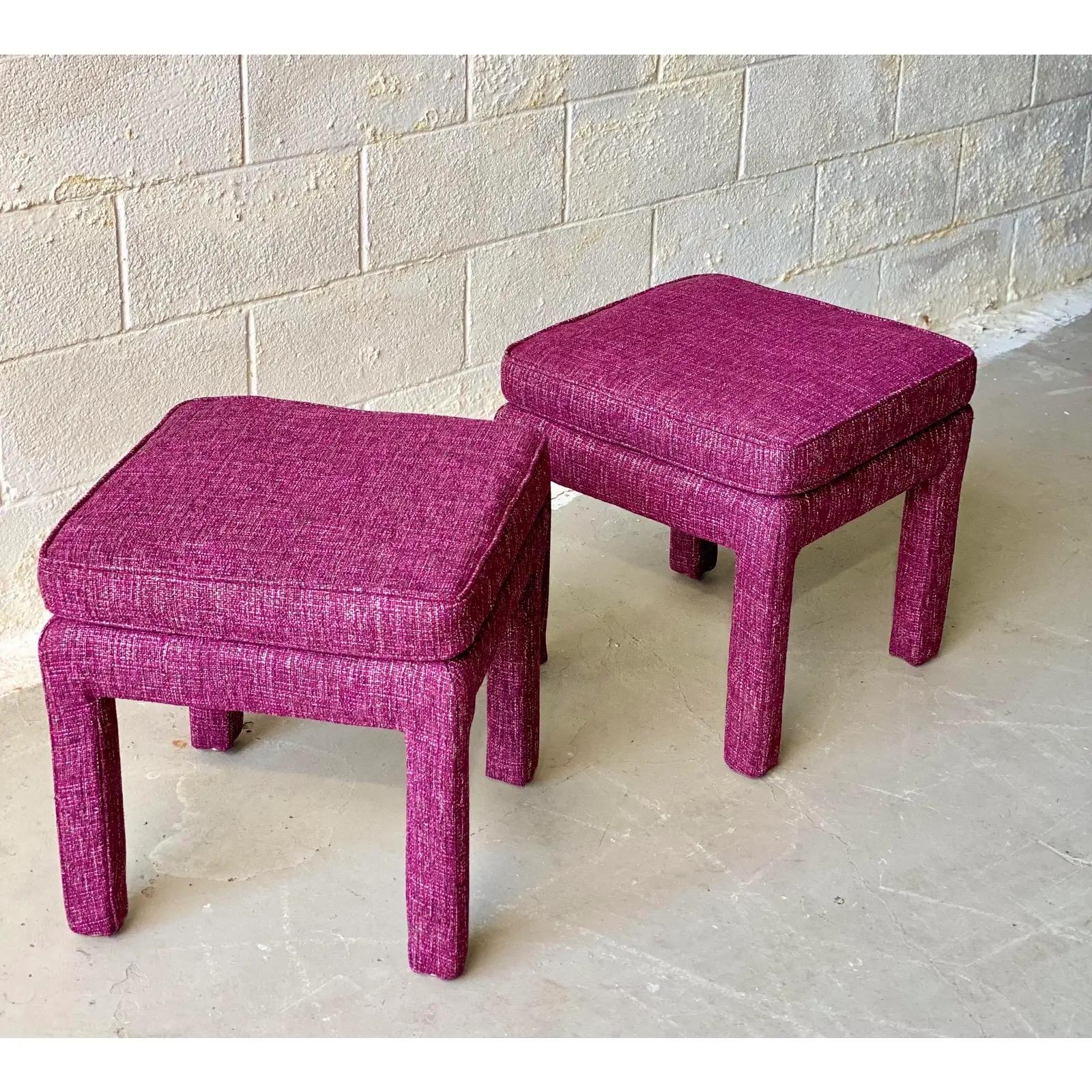 We are very pleased to offer a chic, vintage pair of Milo Baughman style ottomans, circa the 1970s. Layer a space or add extra seating with these eye-catching ottomans wrapped in a new rich, tweed magenta color fabric. In excellent condition and