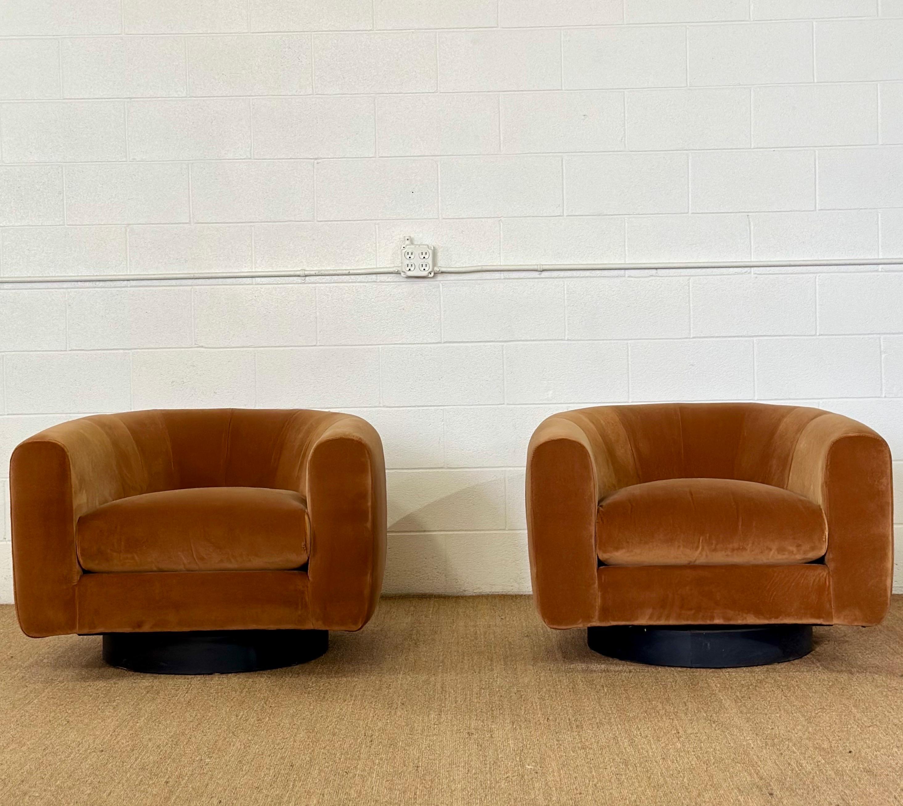 We are very pleased to offer a stunning pair of barrel back chairs in the style of Milo Baughman, circa the 1970s.  Each exquisite chair is anchored upon a sleek black wooden plinth, giving the illusion that the chair is gracefully floating just