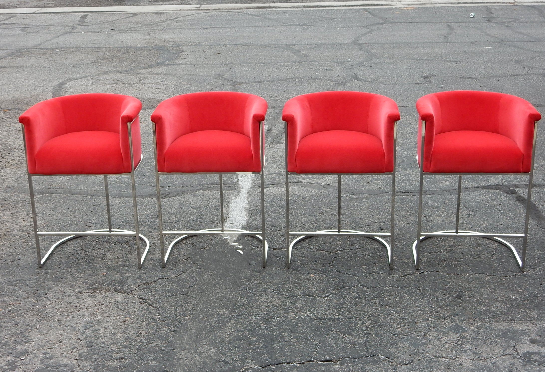 Set of 4 chrome bar stools from the 1970's.
Seamless thin square tube frames with a bucket seating area
upholstered in red velvet.
Tall, counter height standing 33in tall. 
Exceptional quality stools in lightly pre-owned condition. 
They are