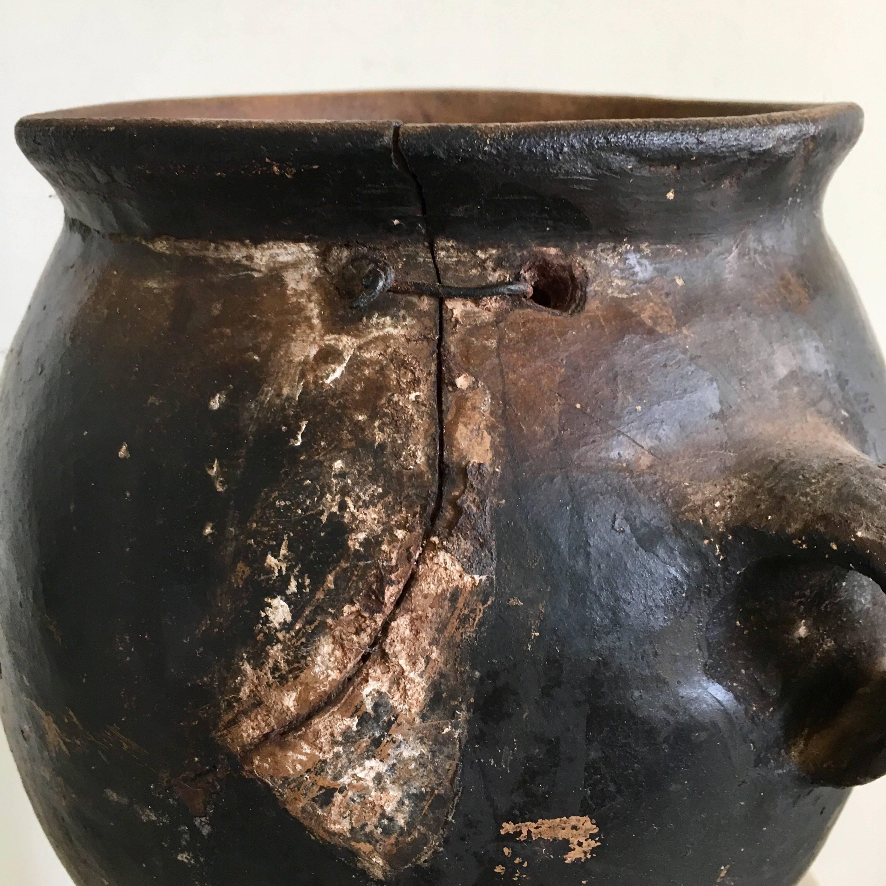 Blackened pot from Los Reyes, Mexico with original staple repair. Primitive design from the Popoloca culture that has remained intact for the last millenia.