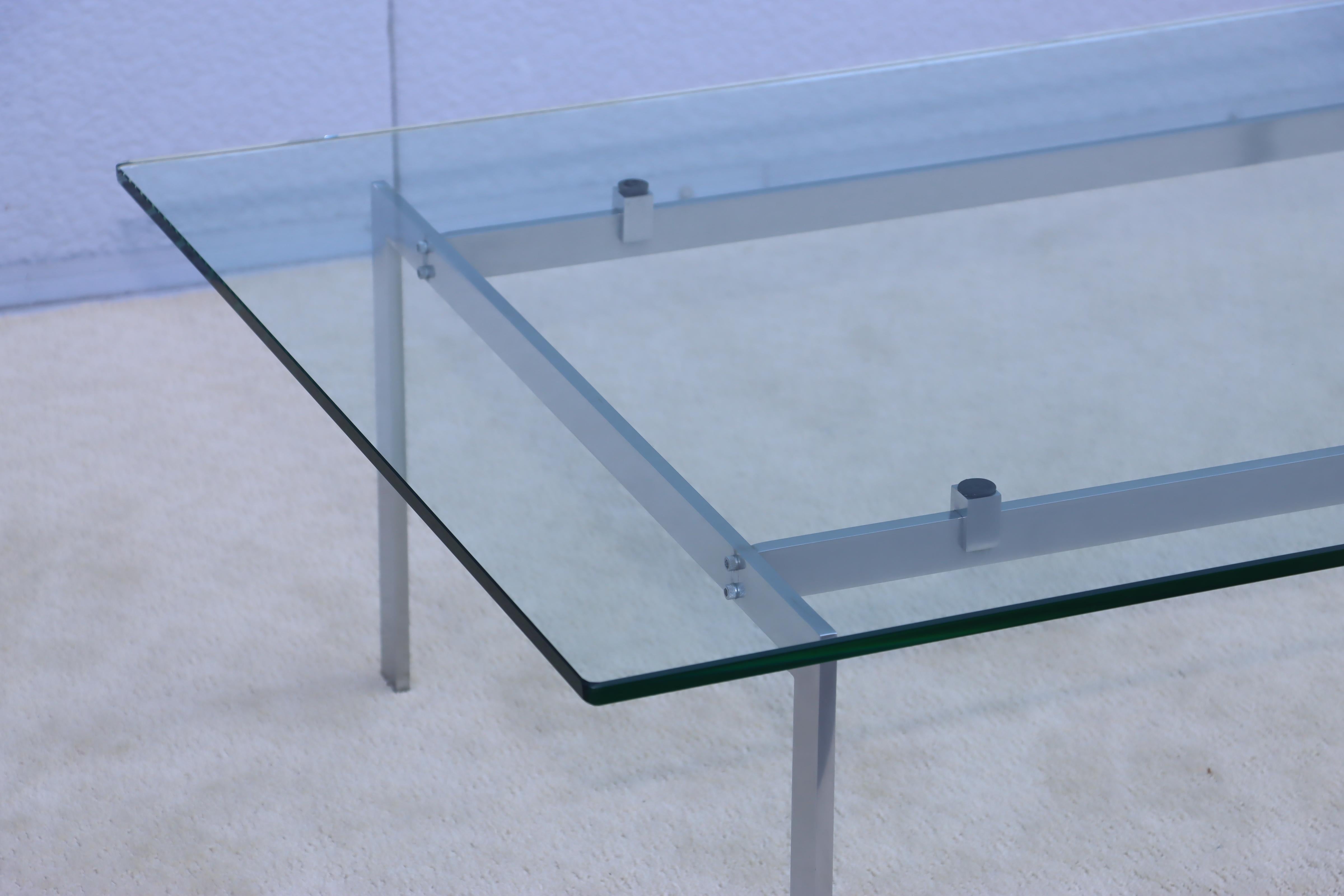 Table basse minimaliste des années 1970 en acier inoxydable avec plateau flottant en verre, en état d'origine vintage avec quelques usures et patines dues à l'âge et à l'utilisation.