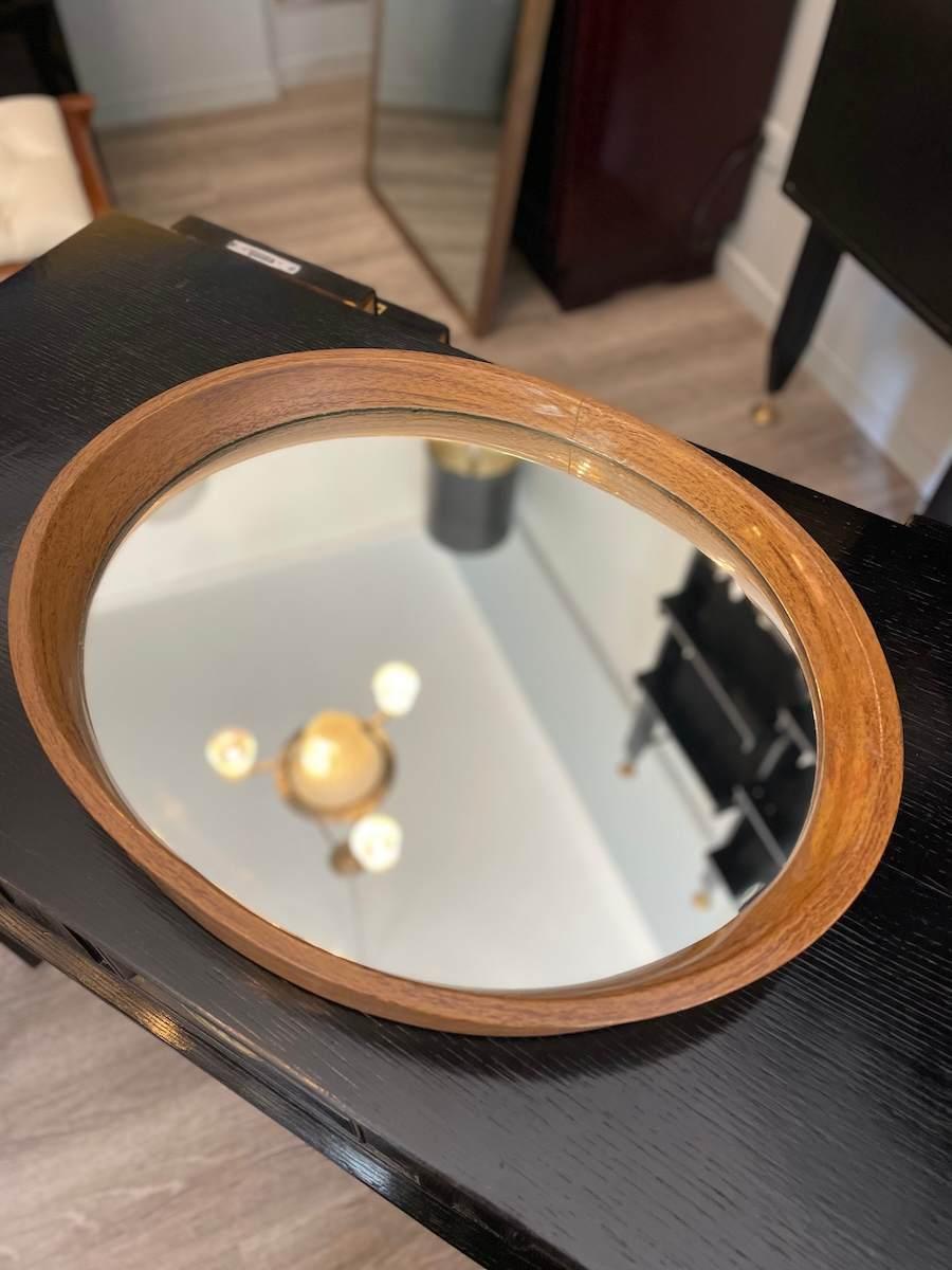 Elegante vassoio ovale degli anni '70 con superficie a specchio e bordo in legno dipinto. Anche la struttura della base è realizzata in legno e reca una firma che ne evidenzia la qualità artigianale. 
Un pezzo decorativo ma funzionale, perfetto per