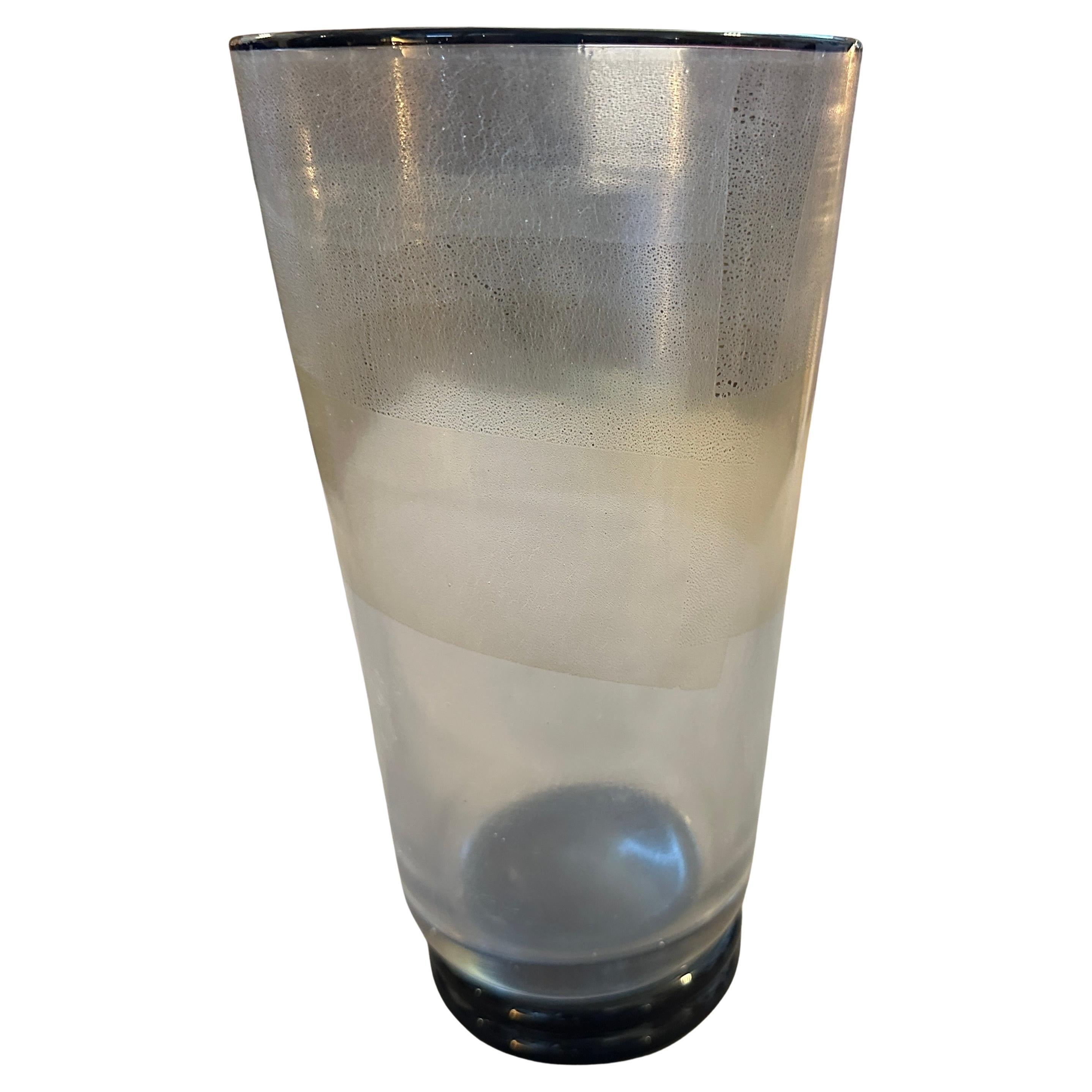 Questo elegante vaso cilindrico alto è un pezzo d'arte italiana vintage, un pezzo distintivo della lavorazione del vetro italiano, realizzato sull'isola di Murano a Venezia durante la metà e la fine degli anni Settanta.
Il vaso ha una silhouette