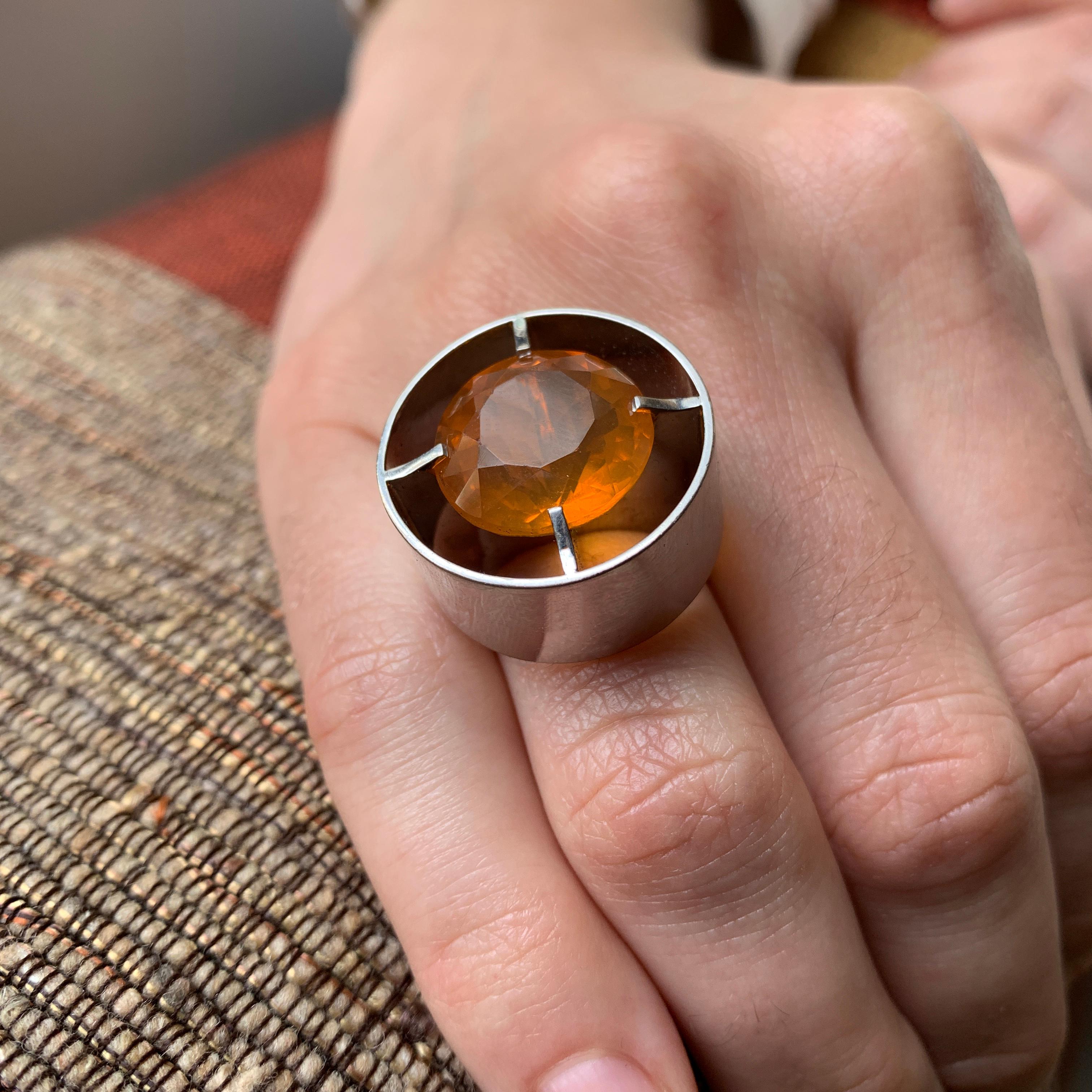 A fire opal and 18 karat white gold cylindrical design ring, c. 1970. The ring is size 6 and with a fire opal of 10.70 ct.