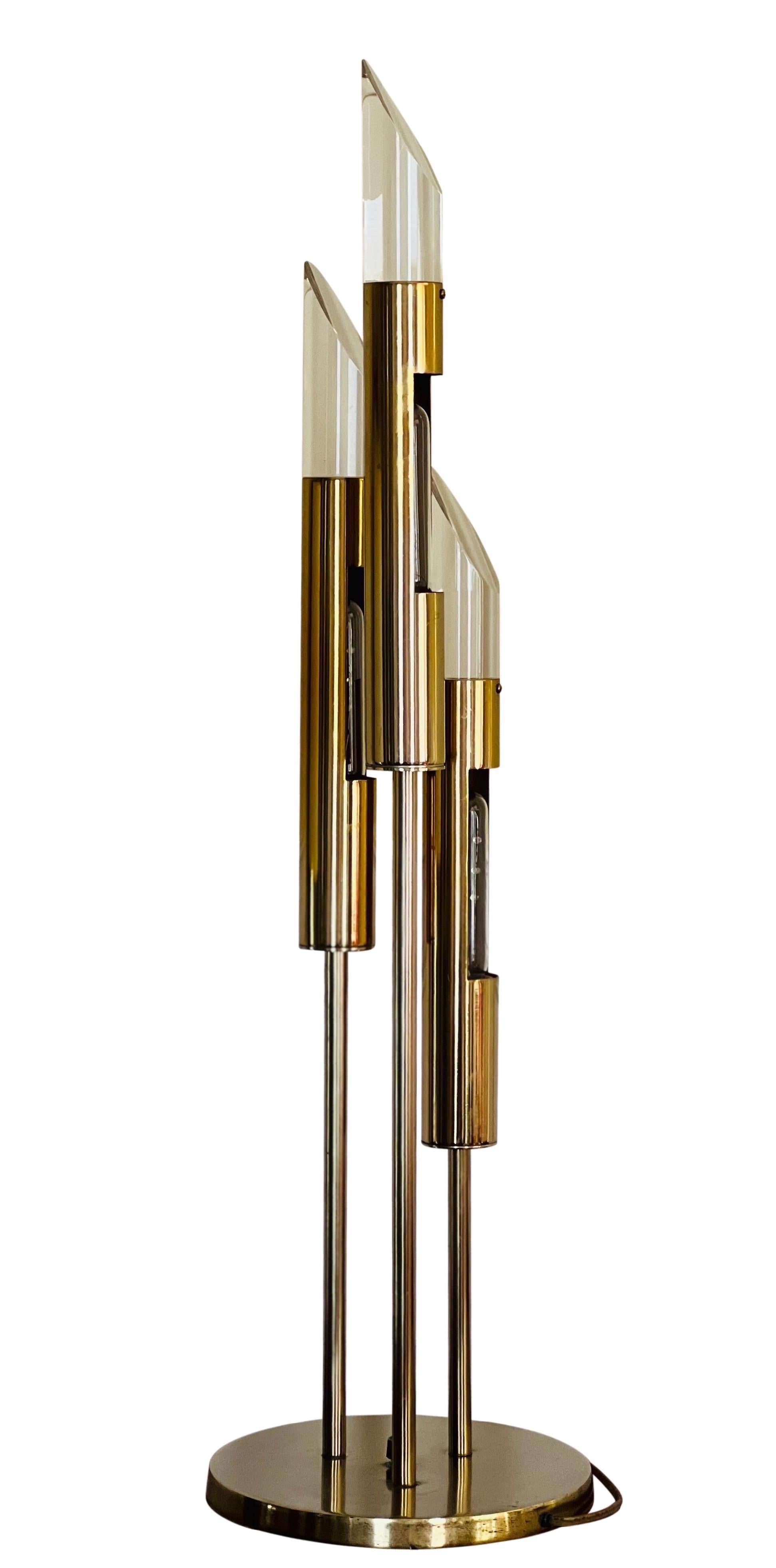 Spectacular vintage modern Italian Space Age table lamp, 1970's.

The lamp features three graduated, tubular shaped lights with slanted lucite tips. It is a combination of brass and brass plated metal. On/off switch is in the center of the base. A
