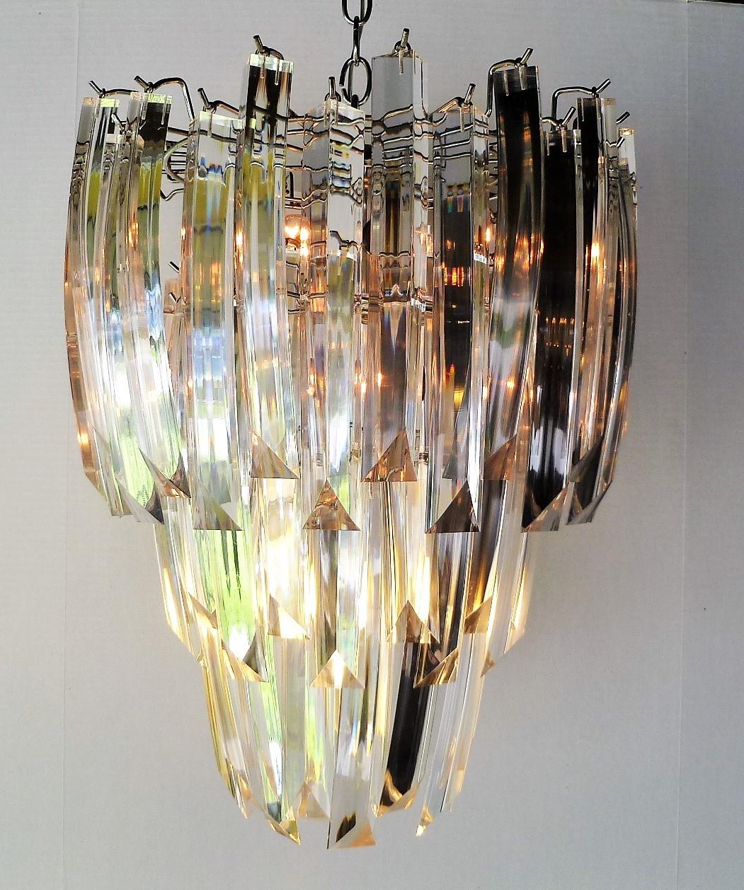 Elegant midcentury three-tier Lucite chandelier form the early 1970s. With a chromed metal frame and three tiers of slightly curving Lucite crystals. A wonderful light source, it has nine chandelier light sockets. Very nice and clean