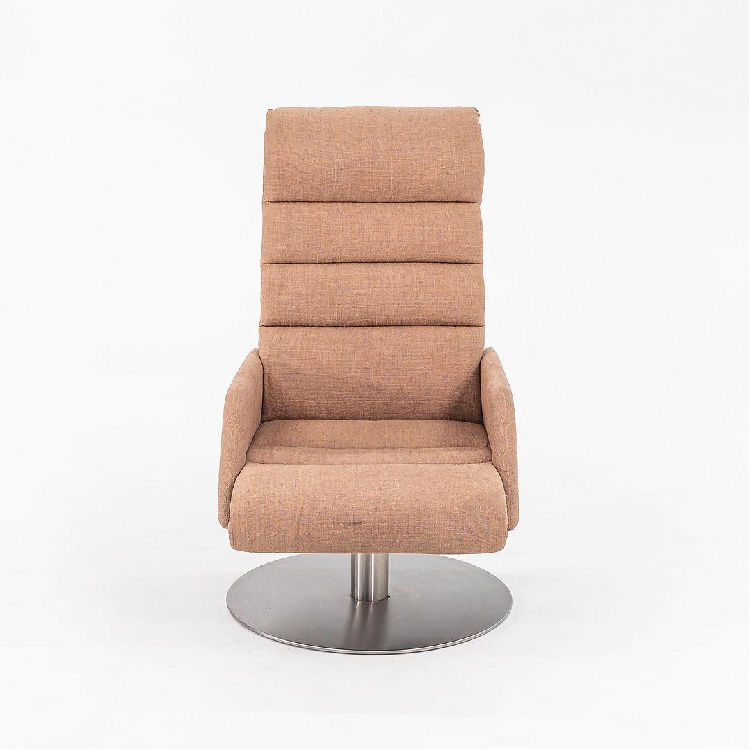 Se trata de una gran Silla de salón giratoria de la década de 1970. Su diseño presenta un mechón de canal horizontal, que ofrece un amplio apoyo ergonómico. La pieza conserva su tapicería original de tela color canela, y tiene una amplia base