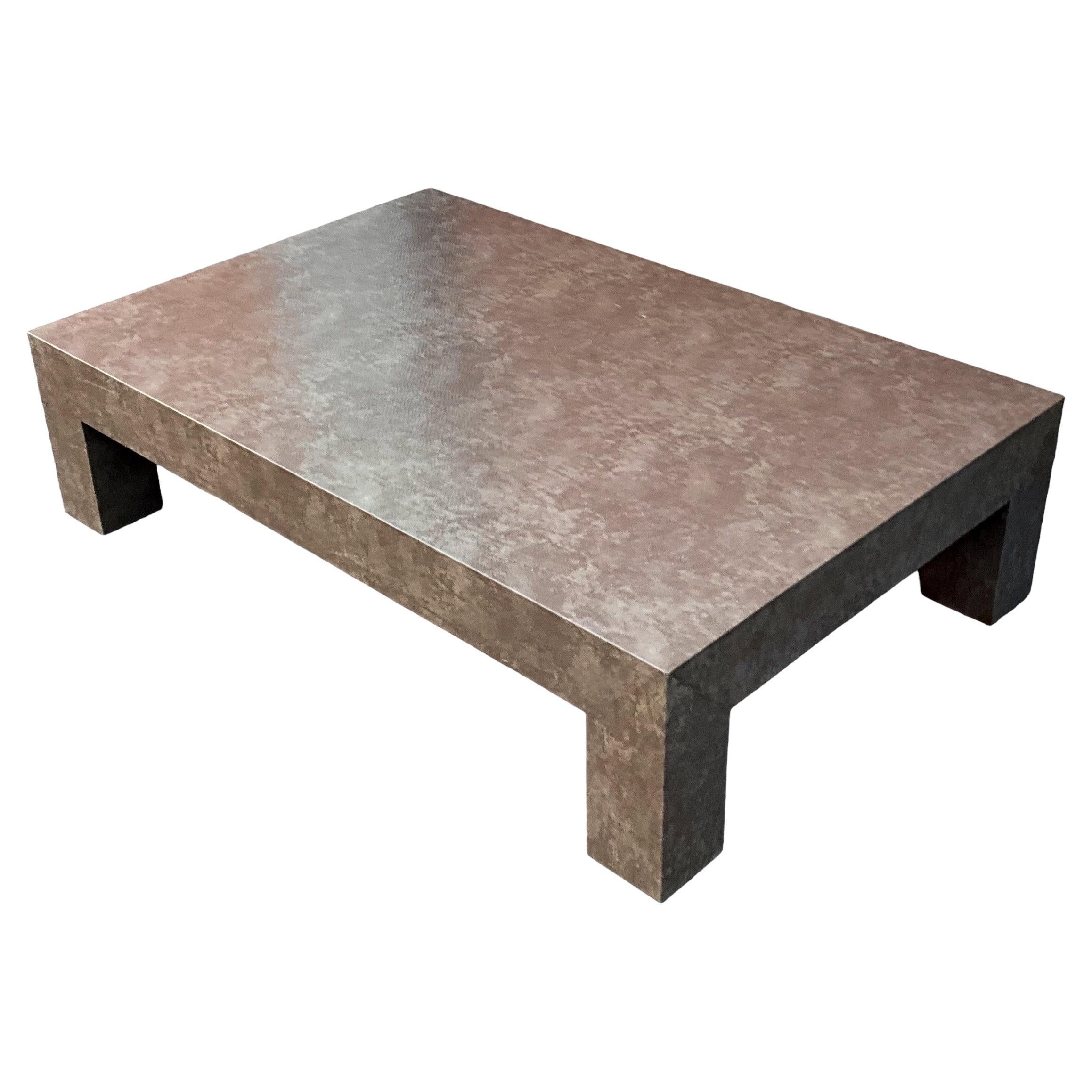 This is a large scale modern Parsons’ style low profile coffee table that has been wrapped in a faux snakeskin. The overall tone is a soothing taupe. It is unmarked and most likely dates to the 70s. 