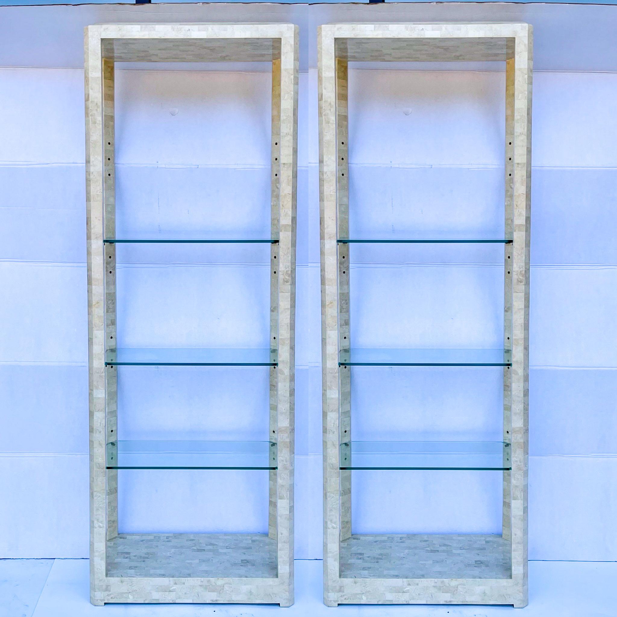 Beautiful in their simplicity and clean lines! This is a pair of 1970s modern tessellated marble etageres that are attributed to Karl Springer. They have adjustable glass shelves and are in very good condition.
